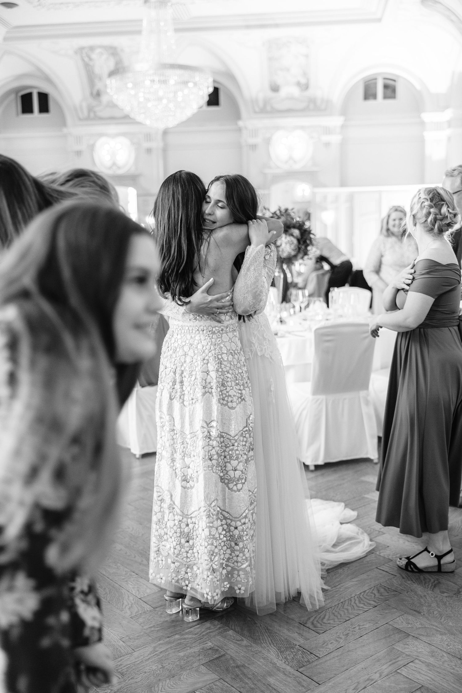 Two people share an embrace on a dance floor at an elegant wedding reception with architectural details. Wedding Photographer Switzerland