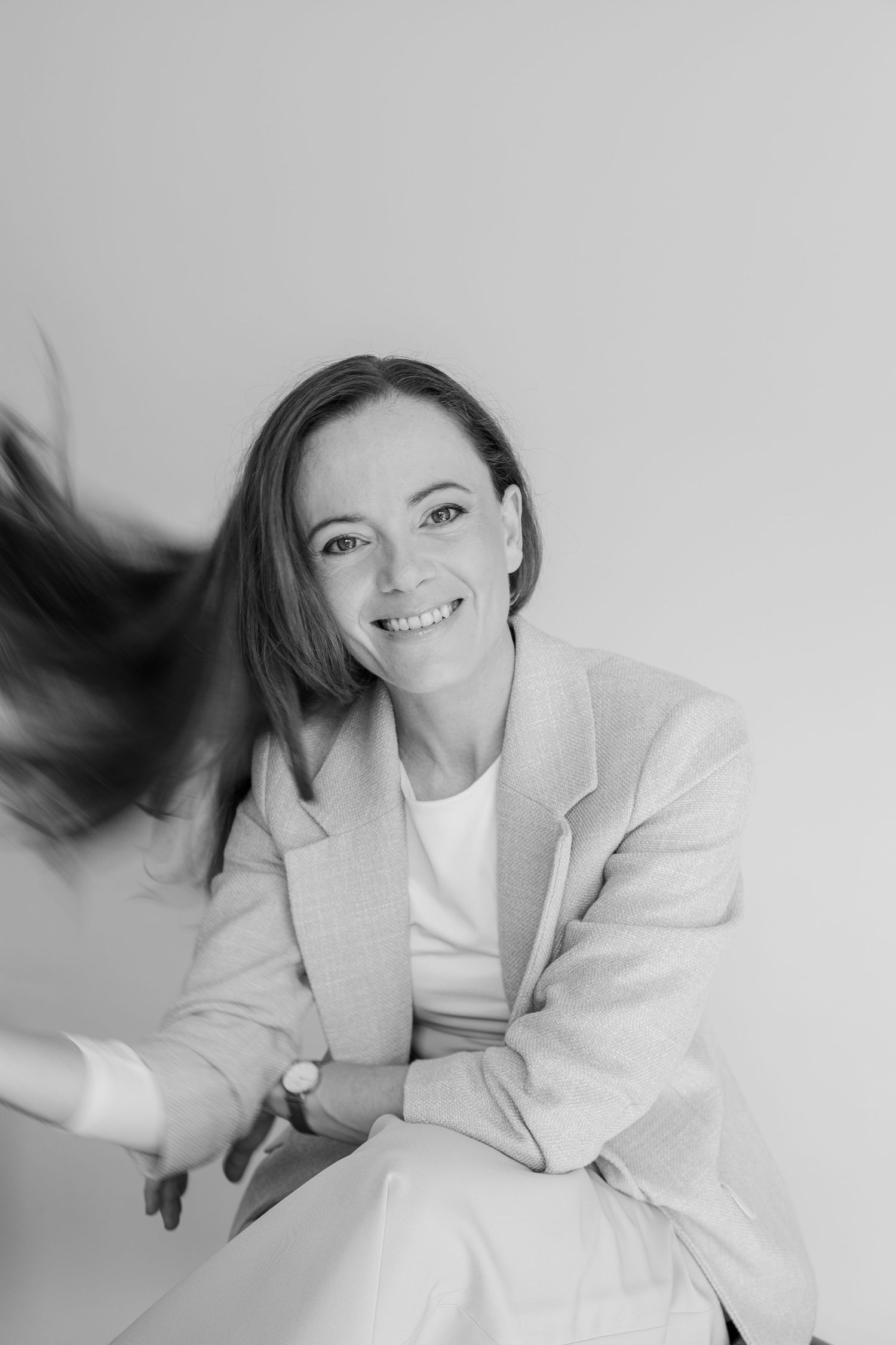 A series of black and white portraits showing a person in a white blazer laying down with flowing hair movement.