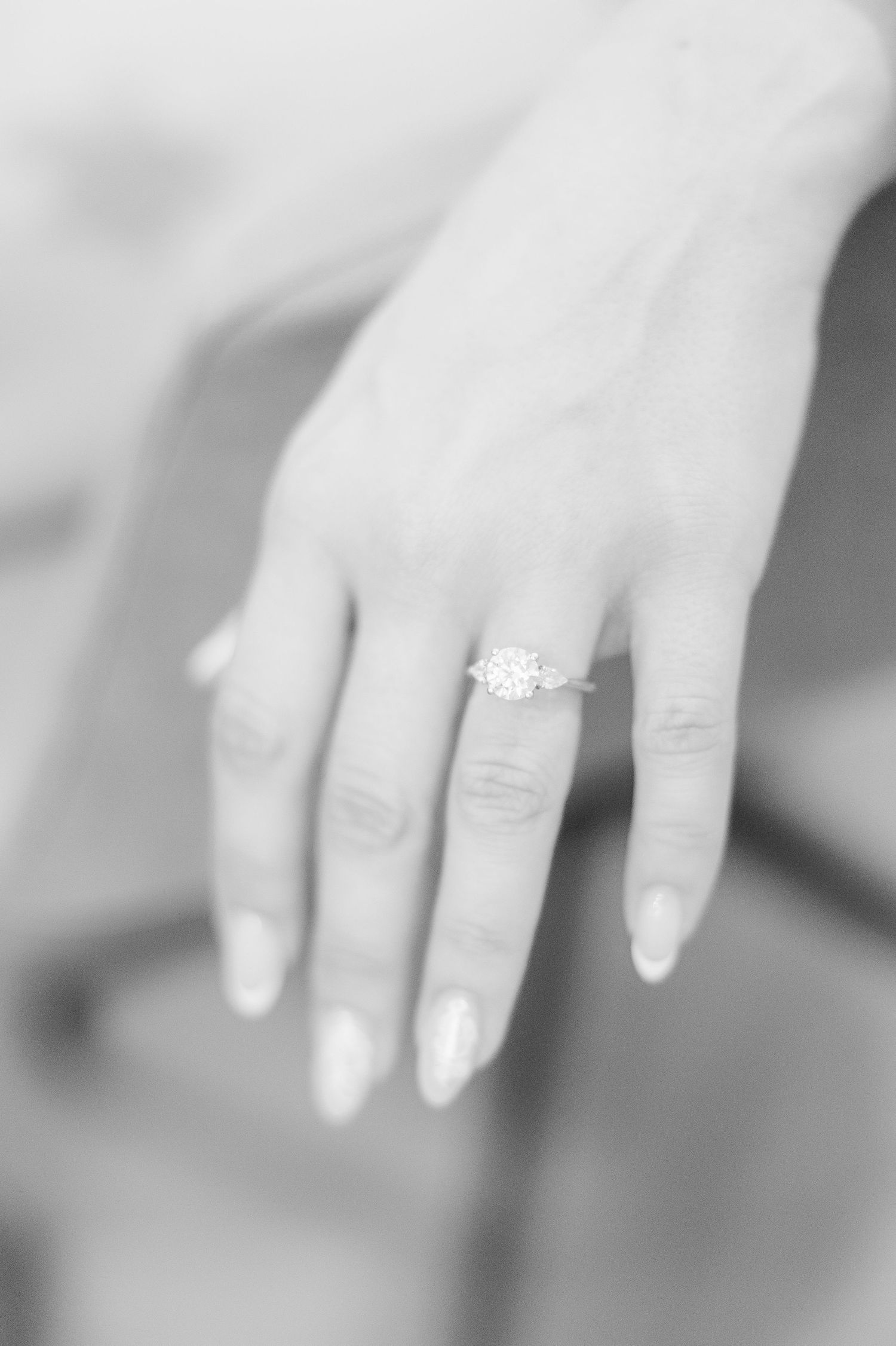Close-up of a womans hand displaying a stunning diamond solitaire engagement ring on her ring finger.