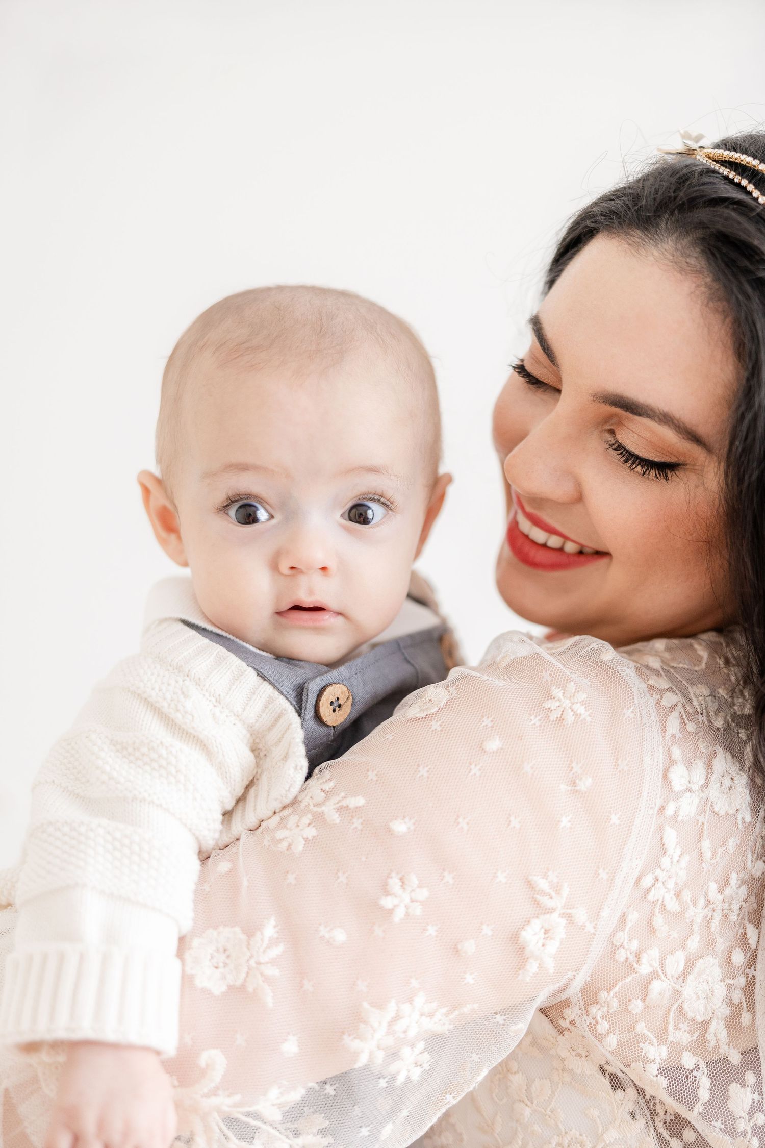 A tender moment between mother and baby in a soft pink and white setting.