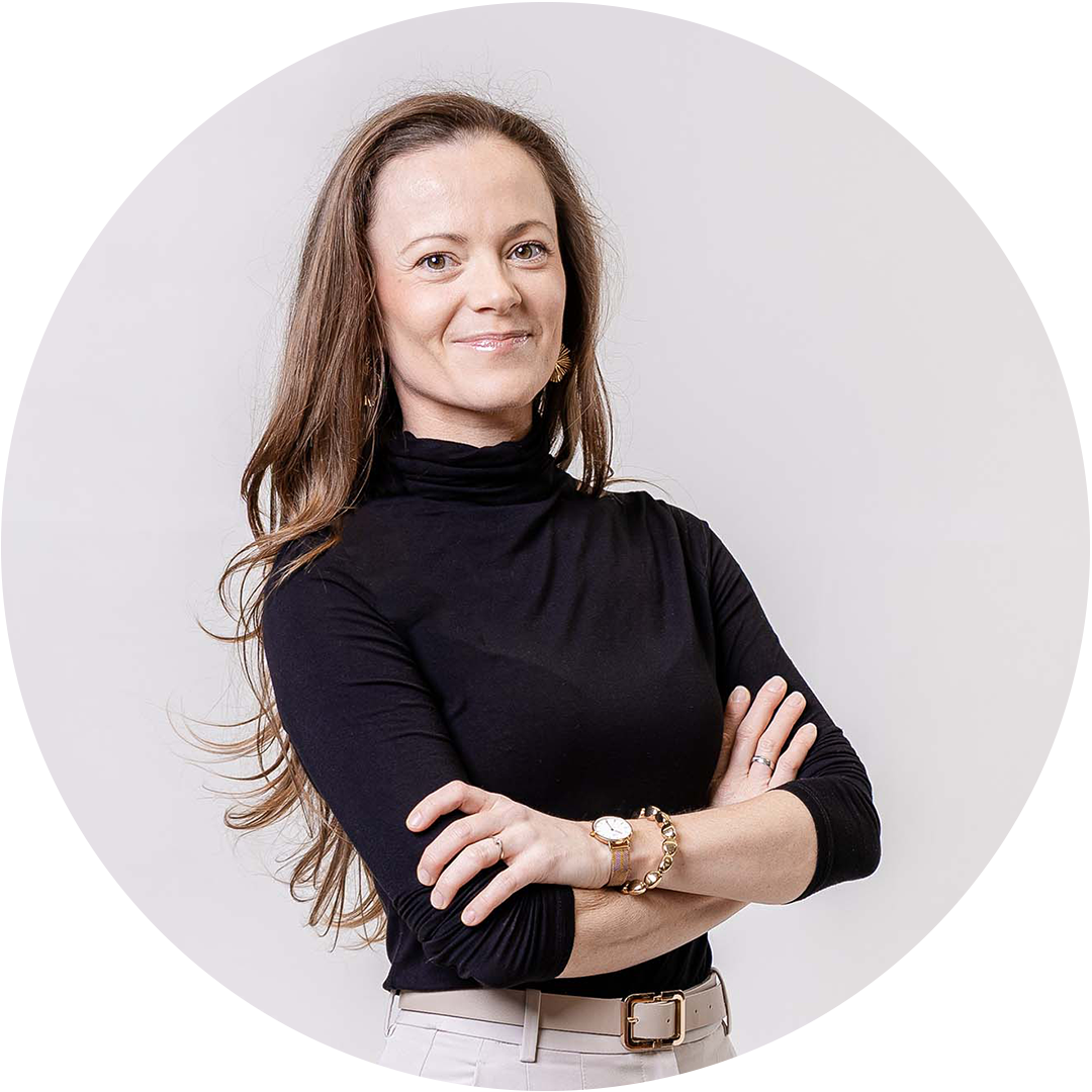 Professional woman with long brown hair in black turtleneck, arms crossed, smiling confidently against light background.