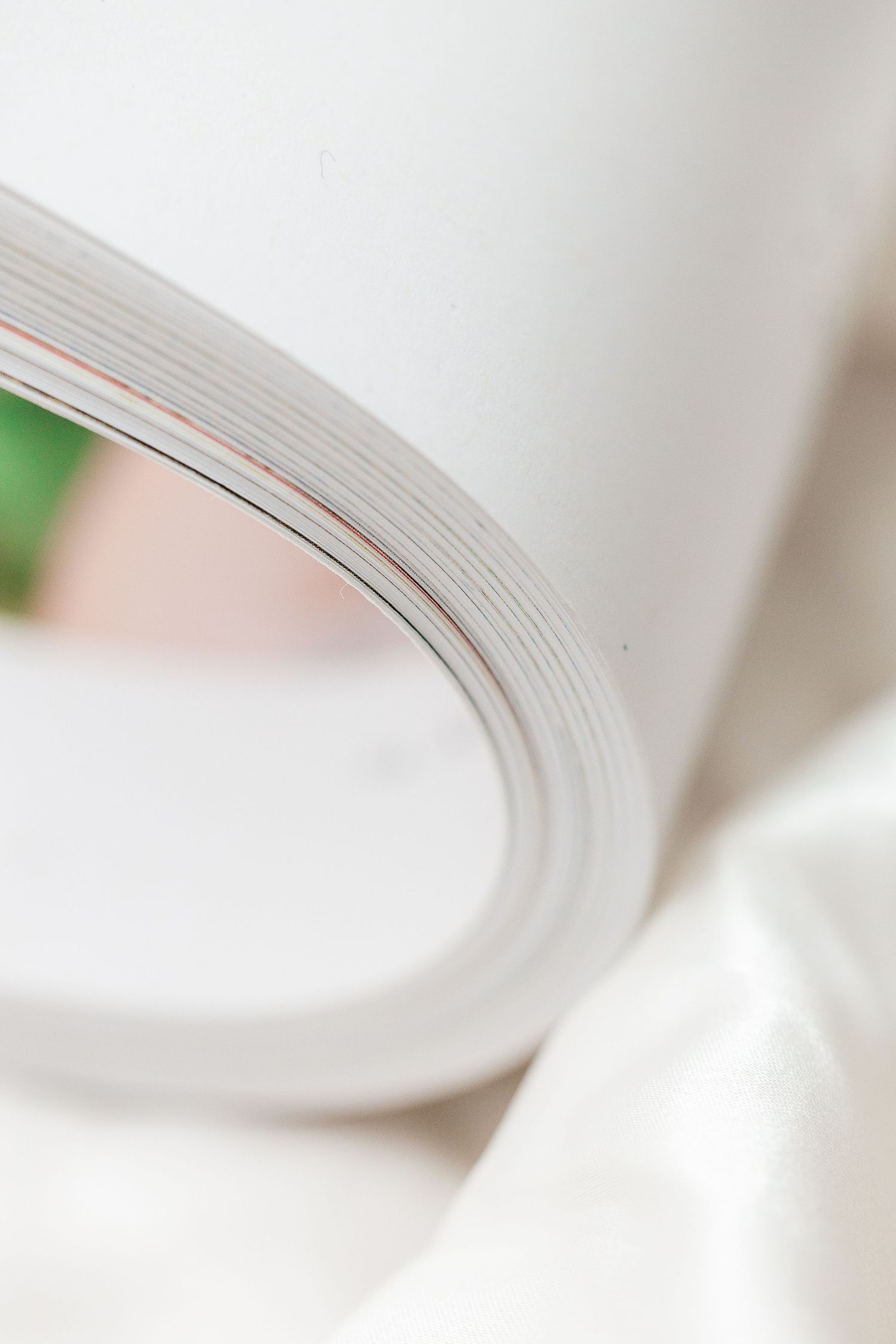 A close-up macro photograph of white book pages fanned out with shallow depth of field.