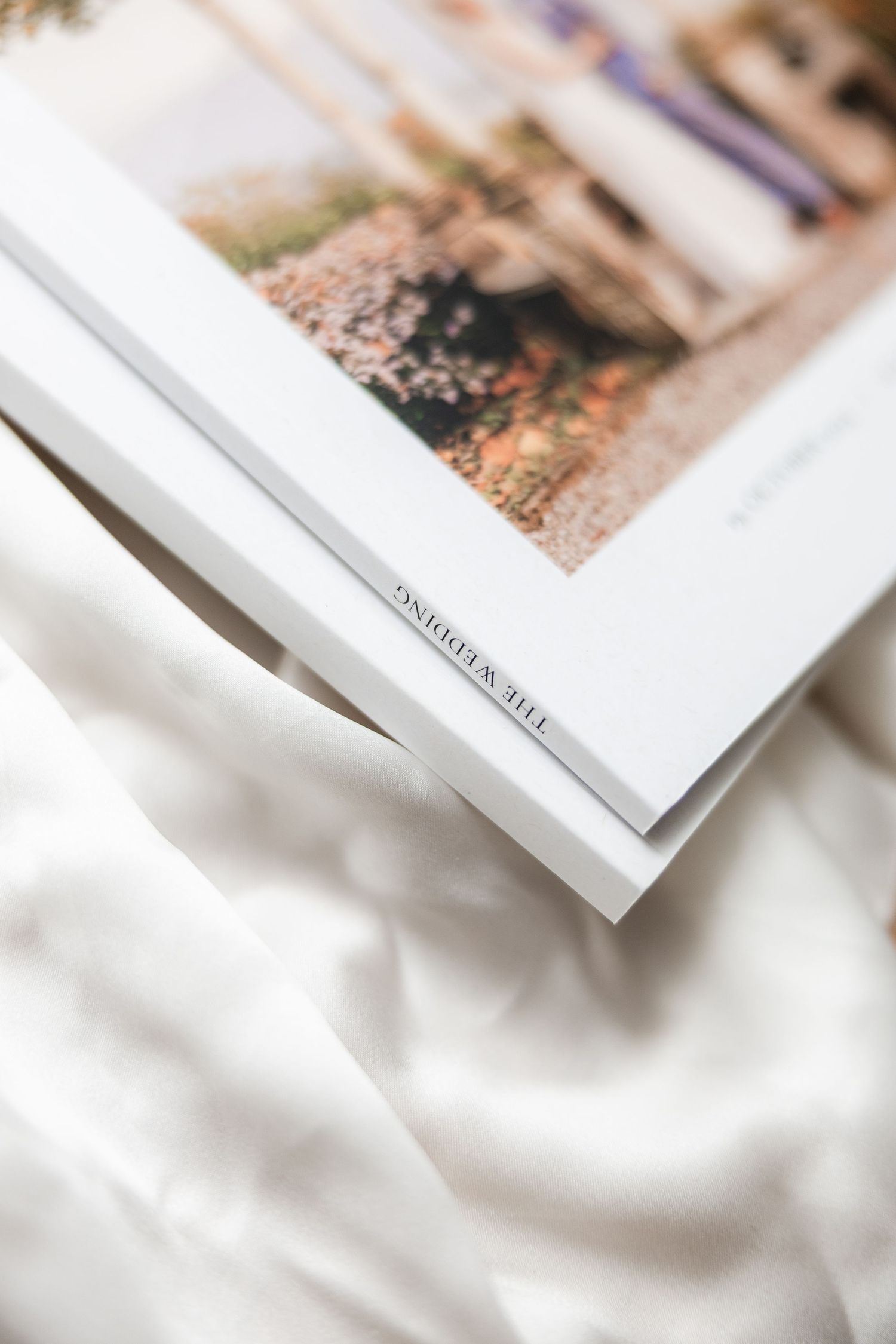 Multiple white photo albums or books arranged in a diagonal line with soft focus and shallow depth of field.
