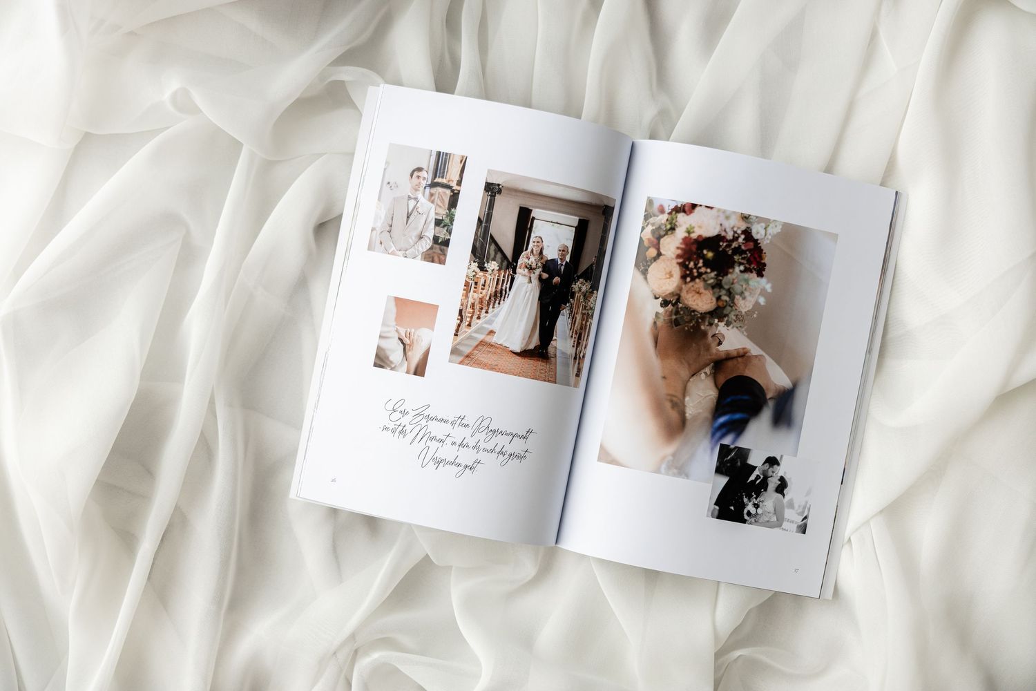 Open wedding photo album with bride portraits and floral bouquet, displayed on white flowing fabric.