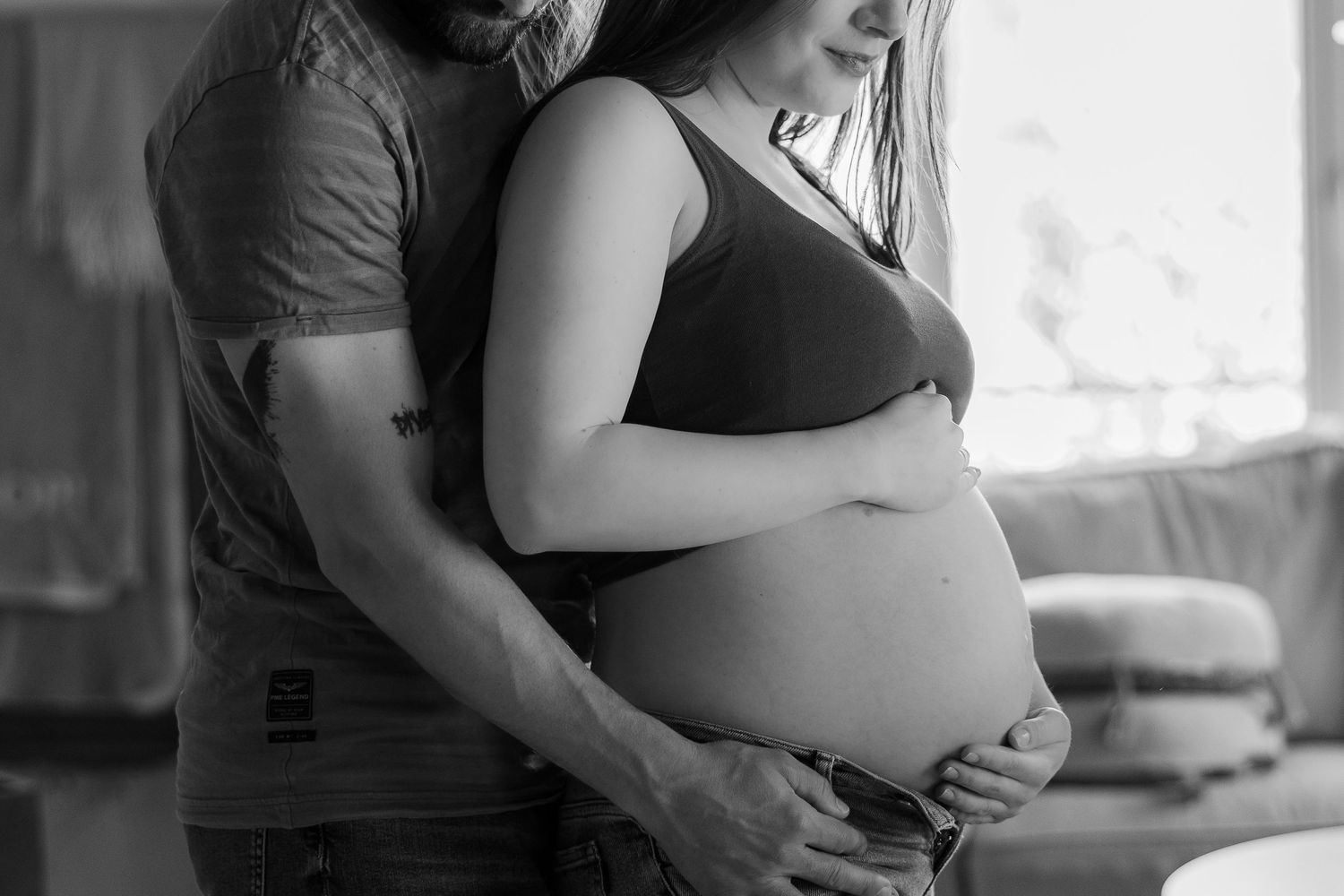 A pregnant woman and her partner share an intimate black and white moment together during a maternity photoshoot.