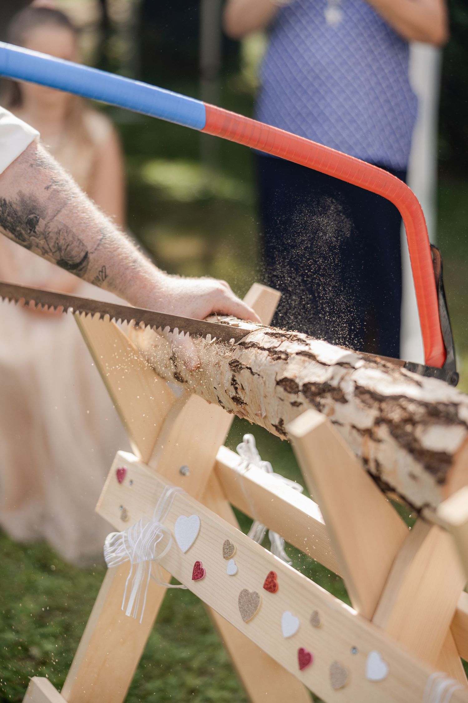 Close-up sequence of wood being cut with a handsaw showing sawdust particles flying in the air.