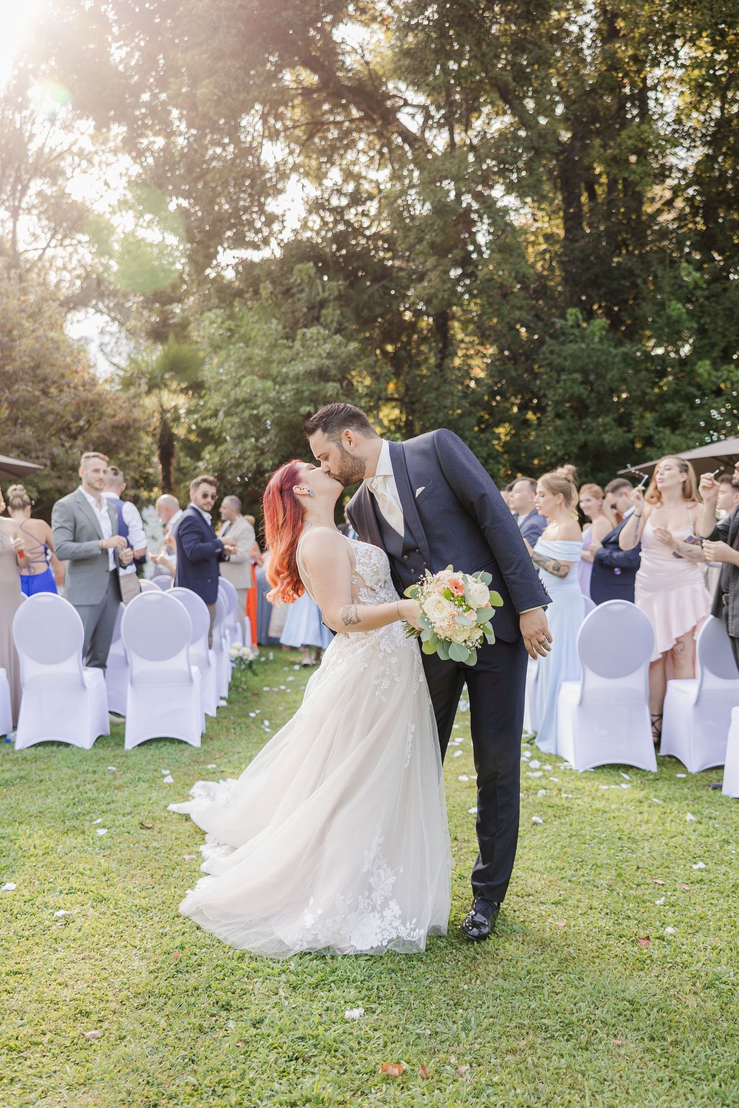 Outdoor wedding ceremony setup with white chair covers and a couple exchanging vows in a natural garden setting - Hochzeitsfotograf Tessin