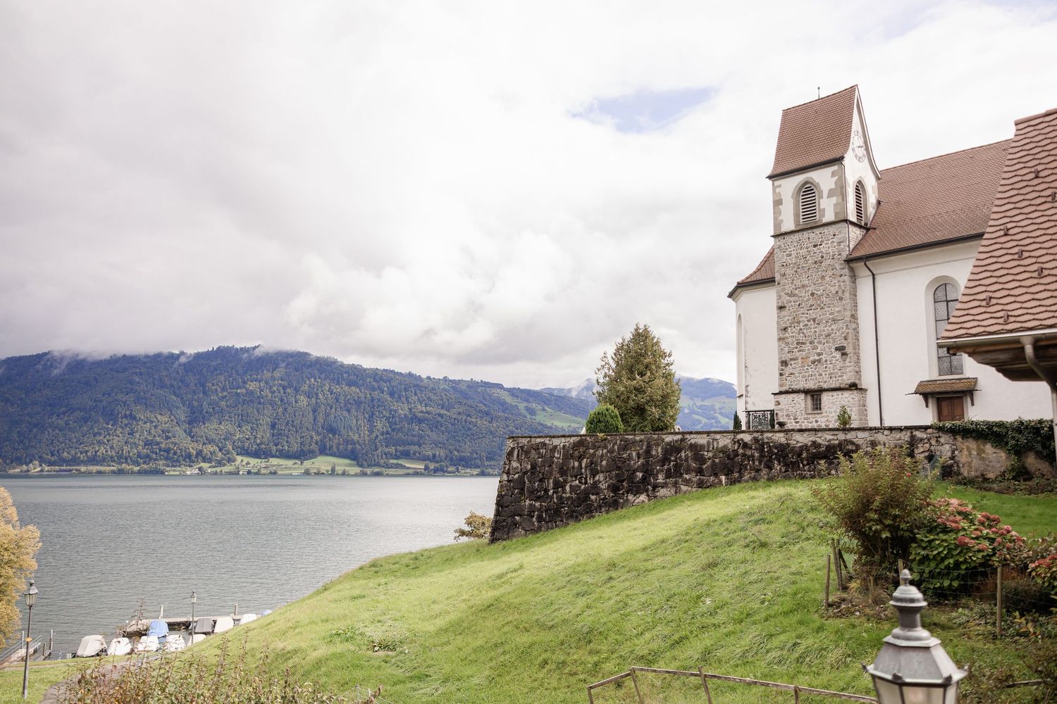 A row of white churches with steeples sits on rolling green hillsides overlooking a misty mountain landscape.