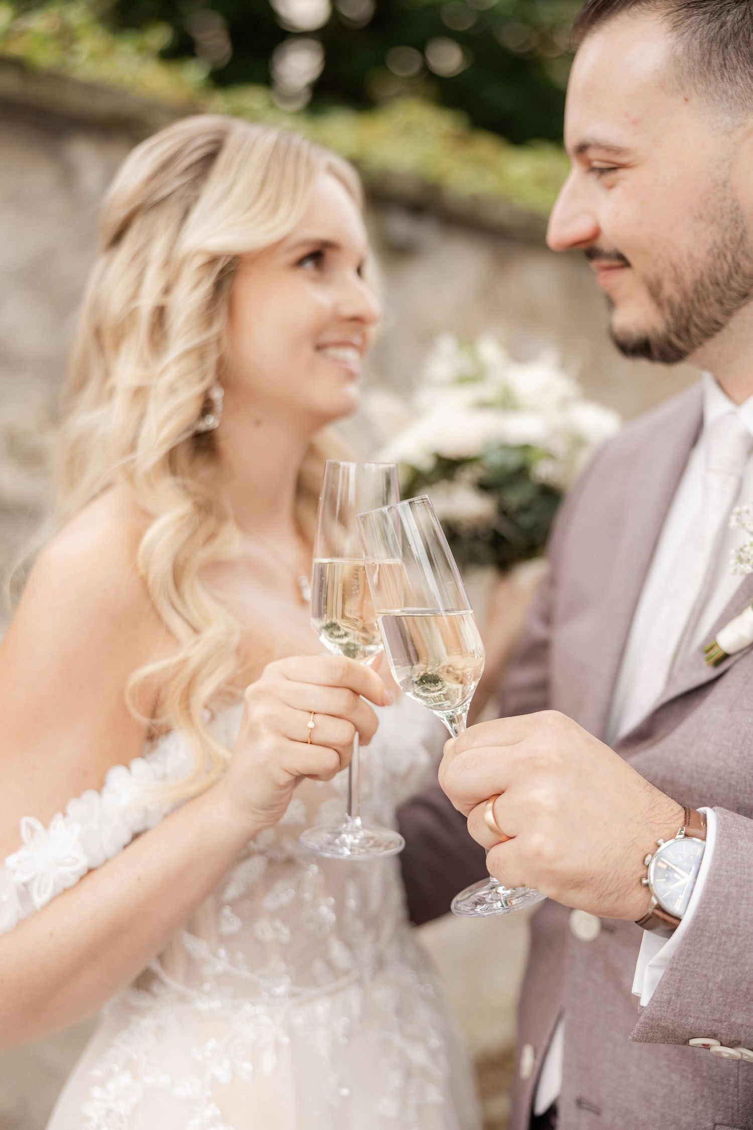 A couple enjoying champagne together at an outdoor wedding celebration while exchanging loving glances.