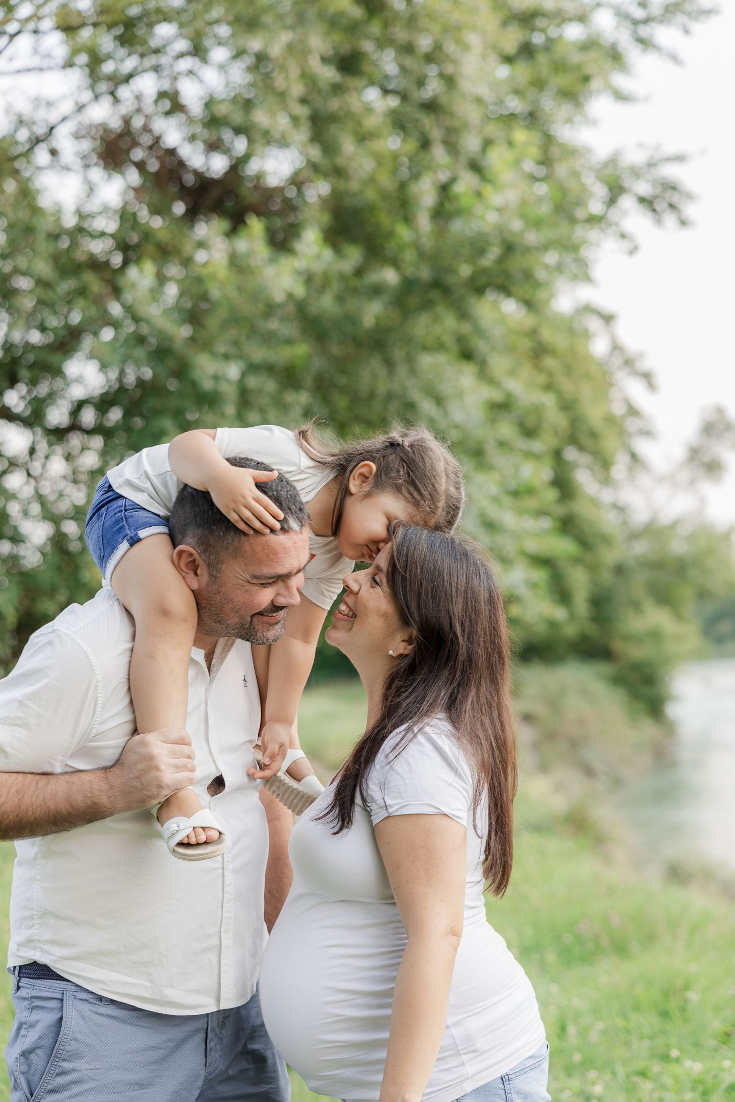 A romantic couple shares tender moments while sitting together in a lush green outdoor setting.