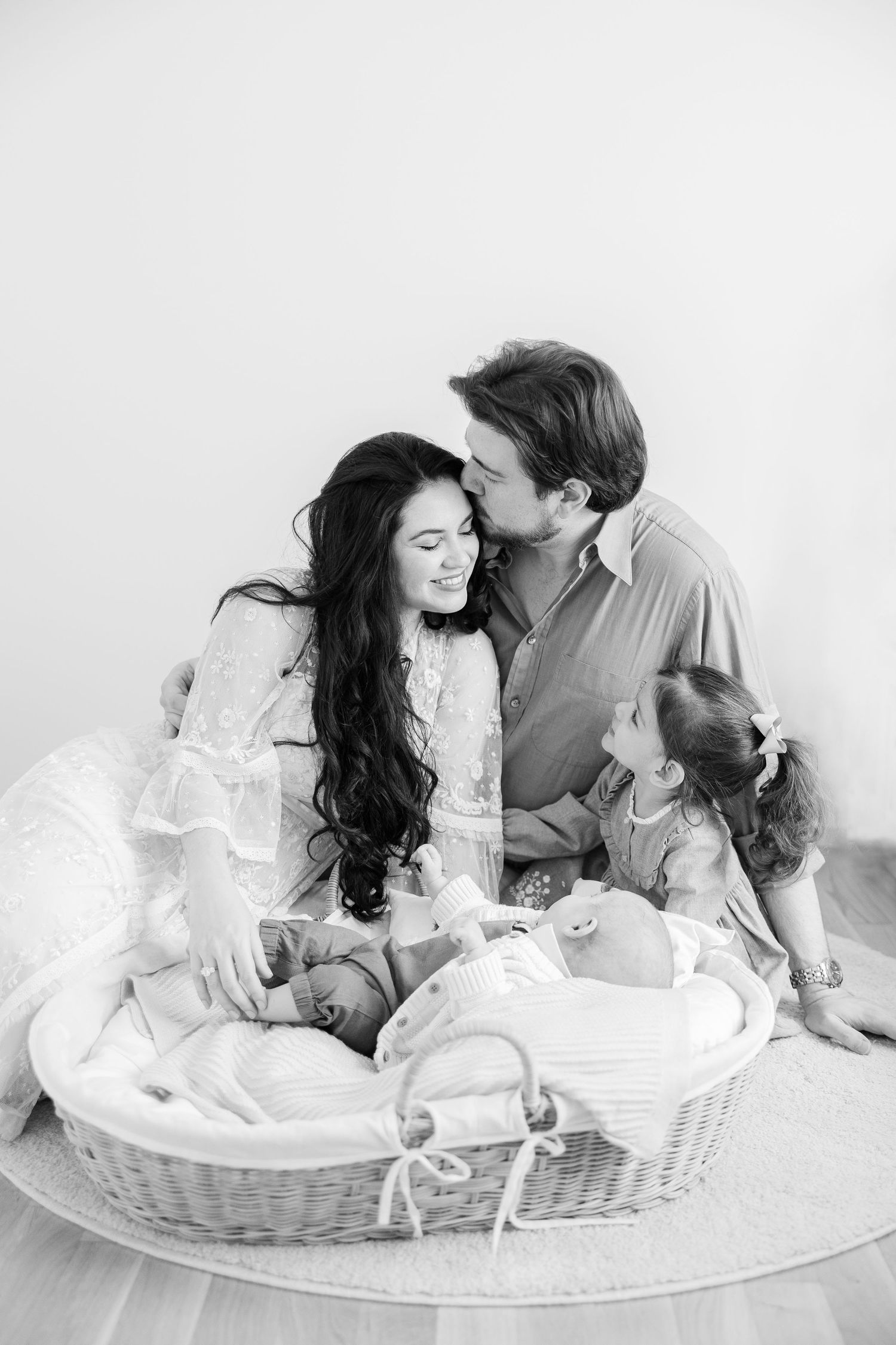 Sweet family moment captured in black and white as couple shares tender moment with baby in wicker basket.