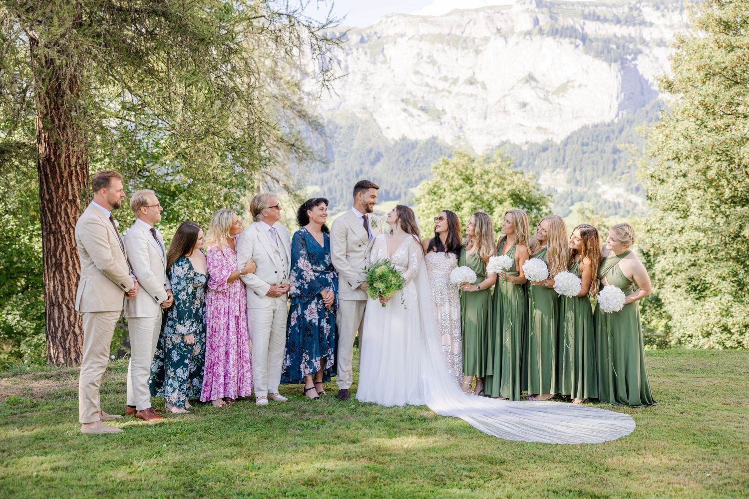 Wedding party poses together in a scenic outdoor setting with mountains and trees in the background.