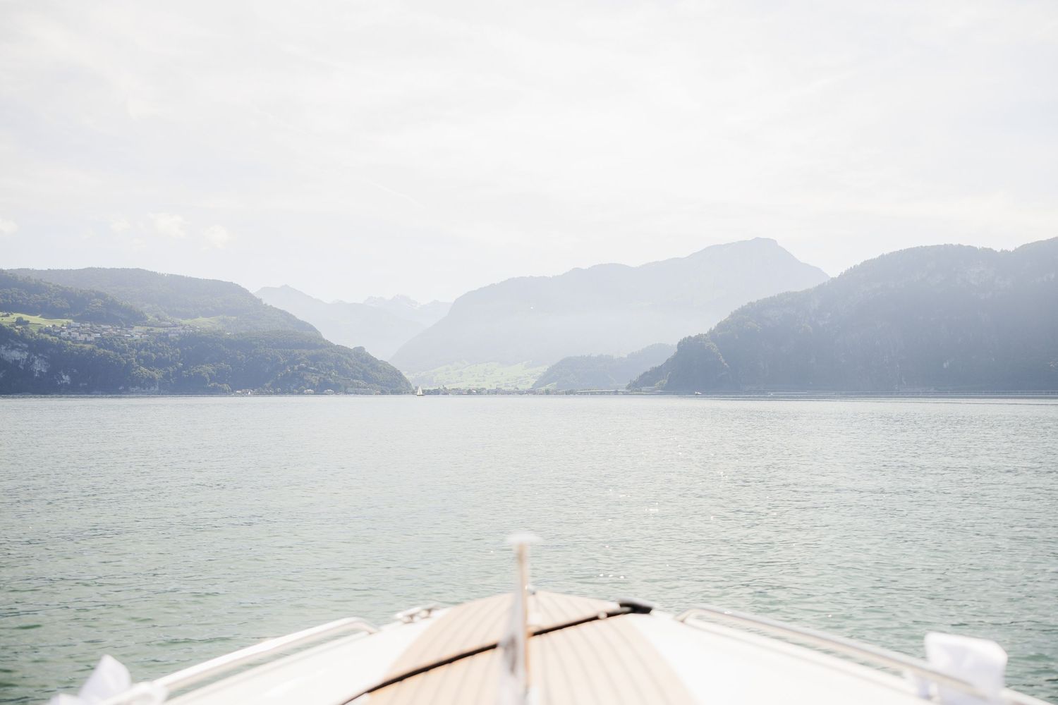 Scenic panoramic view of a misty lake surrounded by mountains with a boat dock in the foreground.