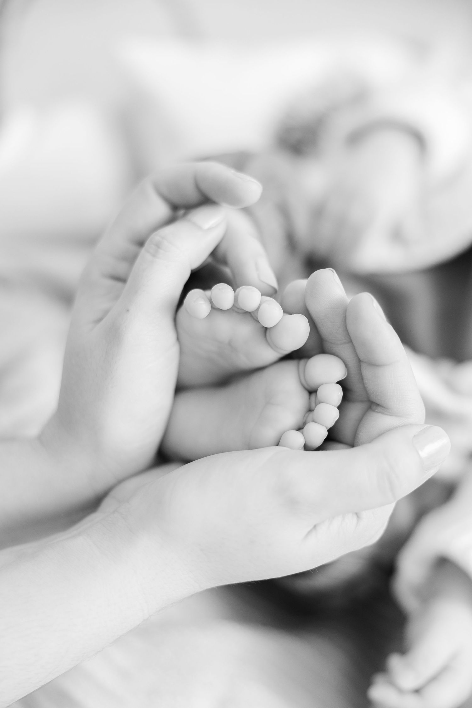 A tender black and white close-up of tiny baby fingers grasping an adult's finger in a series of connected images.