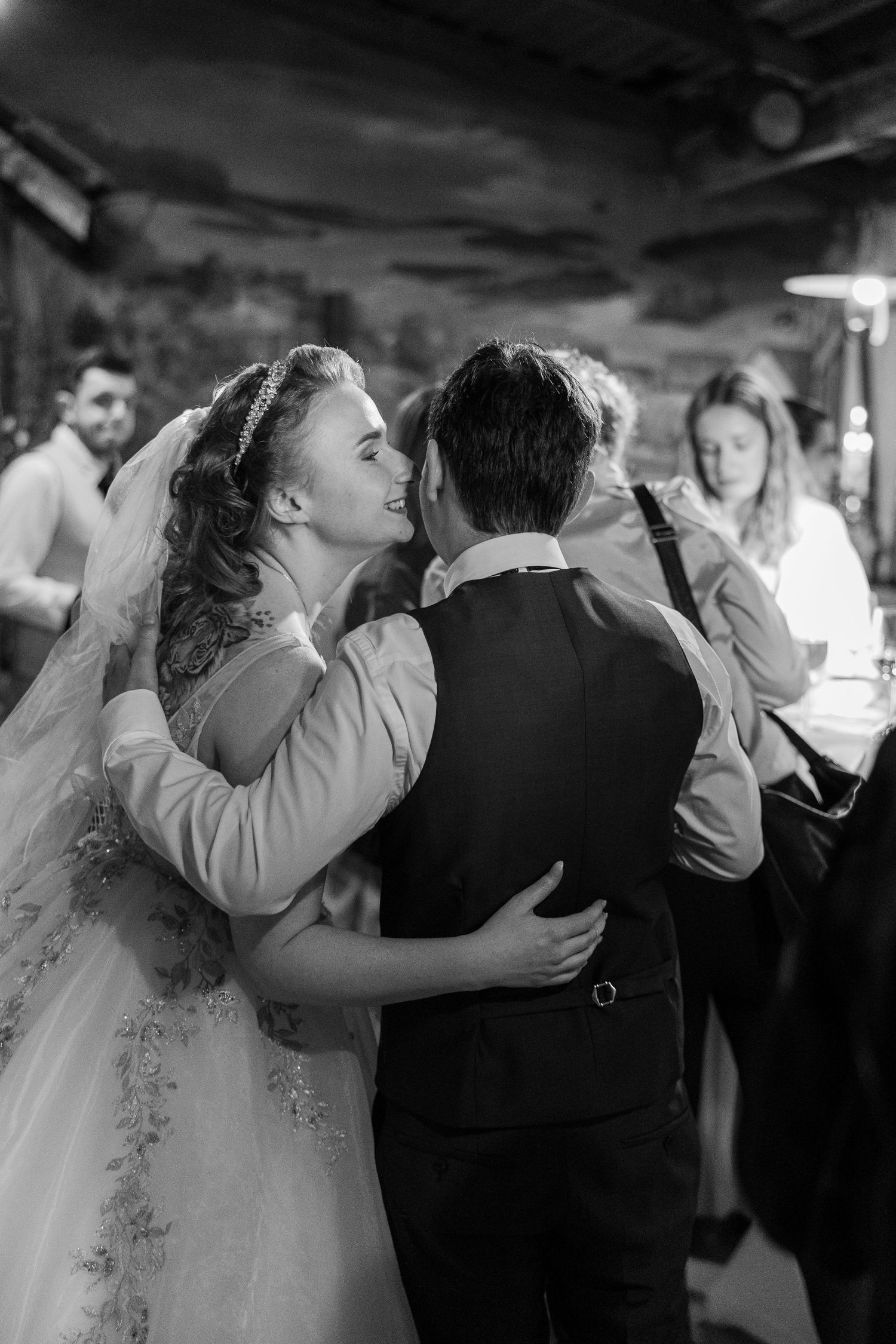 Black and white photo of a bride and groom sharing their first dance at a wedding reception.
