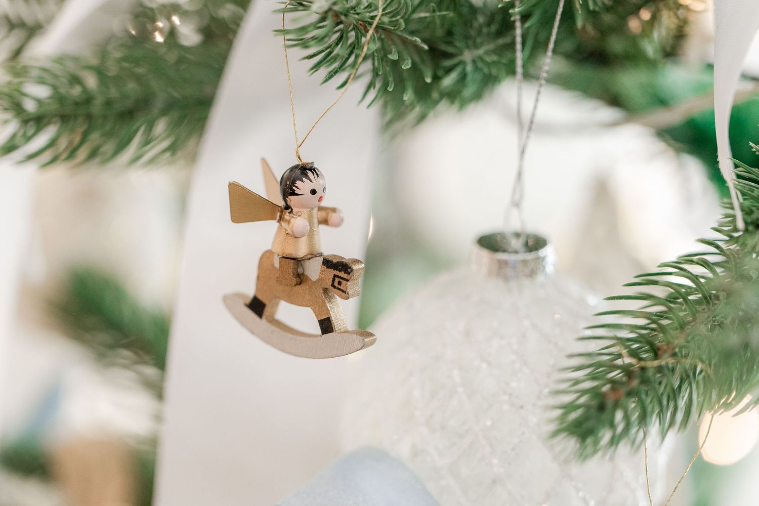 Delicate wooden ornaments and evergreen branches create a cozy Christmas tree decoration scene.
