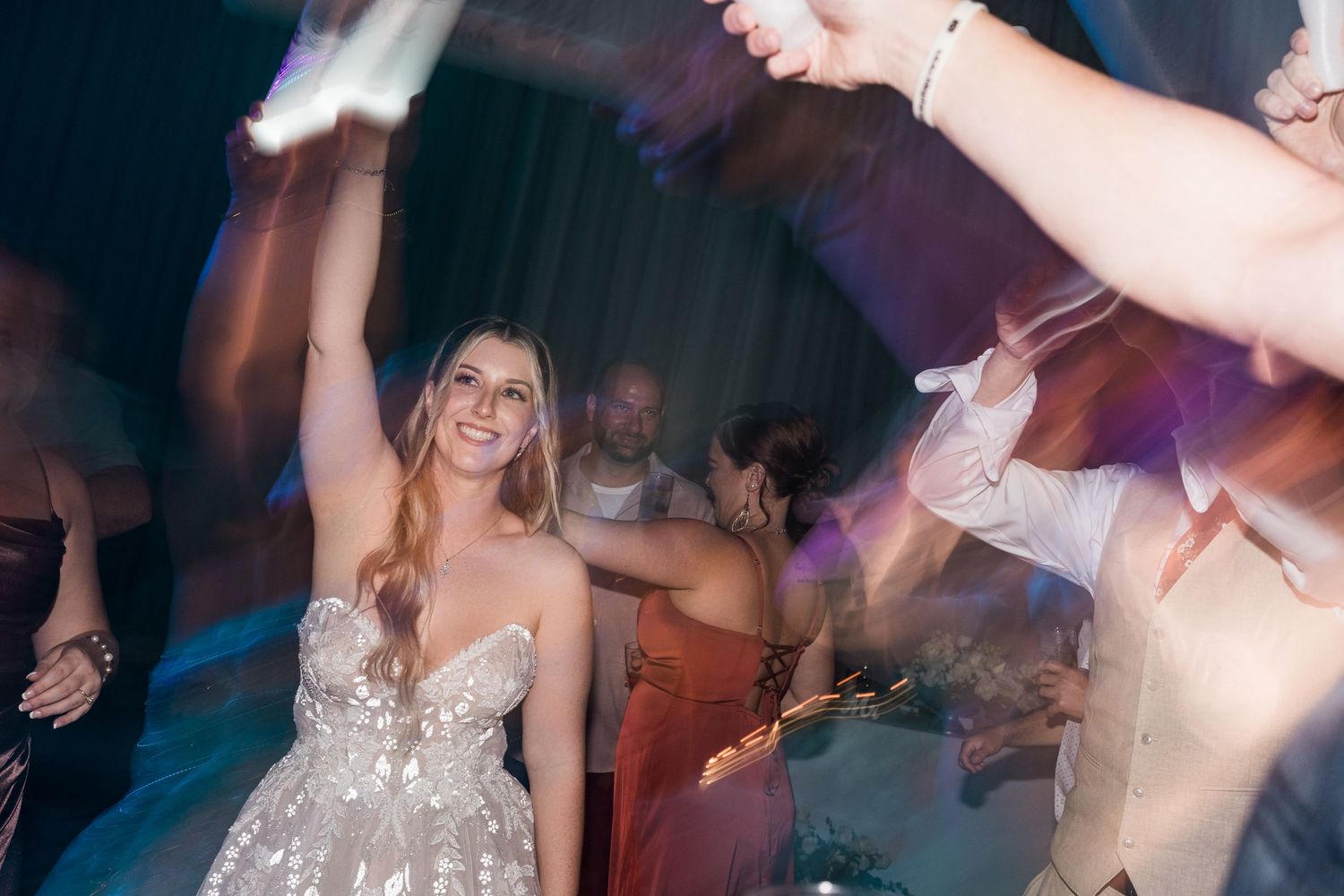 Bride in a sparkling wedding gown dancing joyfully at her wedding reception.