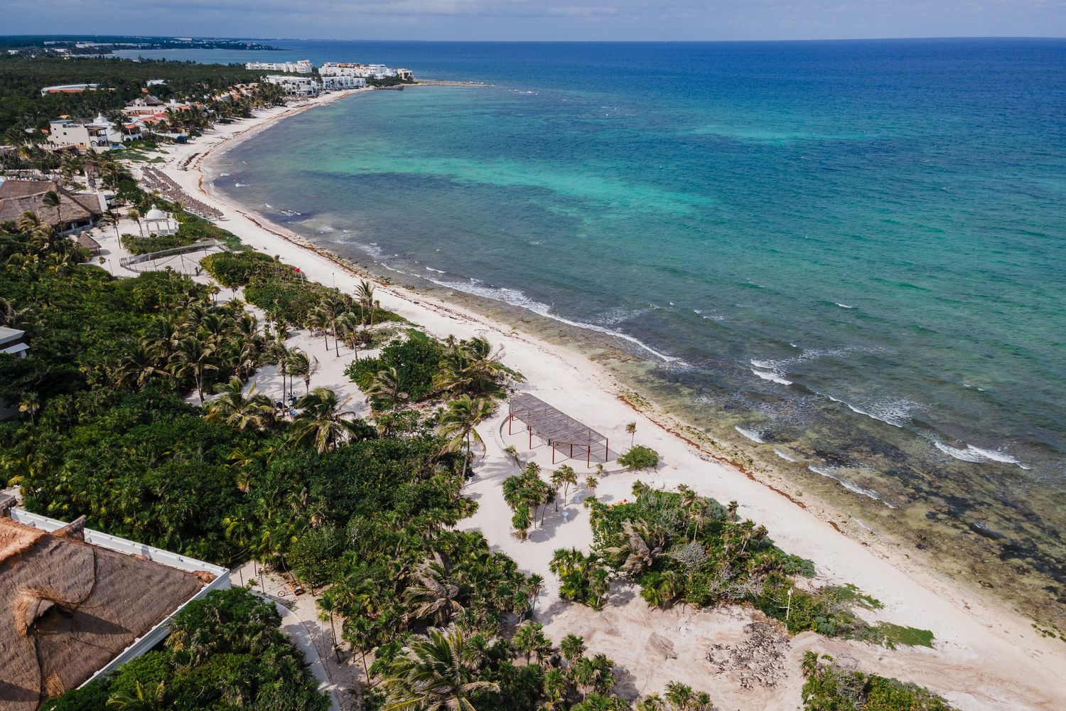 Aerial view of Caribbean coastline with turquoise waters, white sand beach, and lush tropical vegetation.