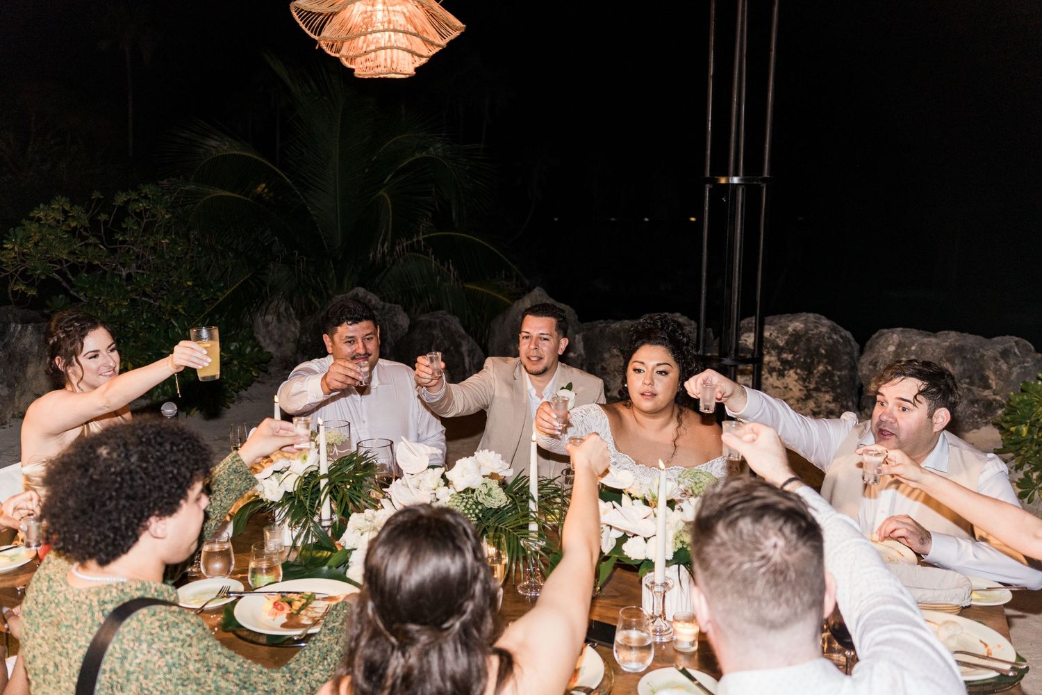 Xcaret Arte Wedding party raises glasses in a toast at an elegant outdoor nighttime reception