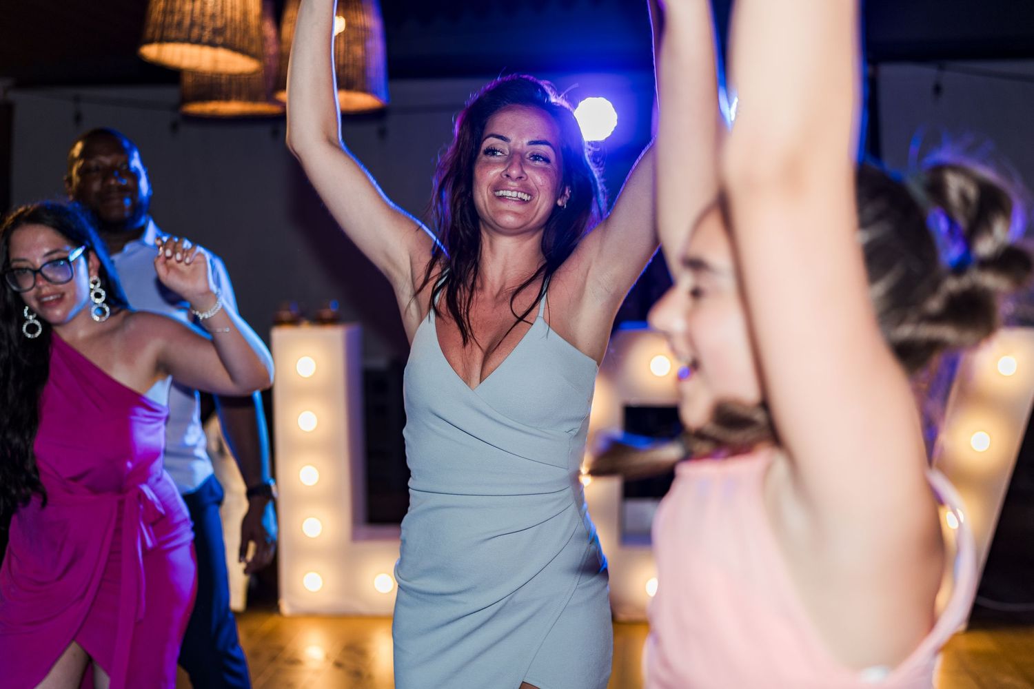 Guests dancing joyfully under marquee lights at an elegant wedding reception party.
