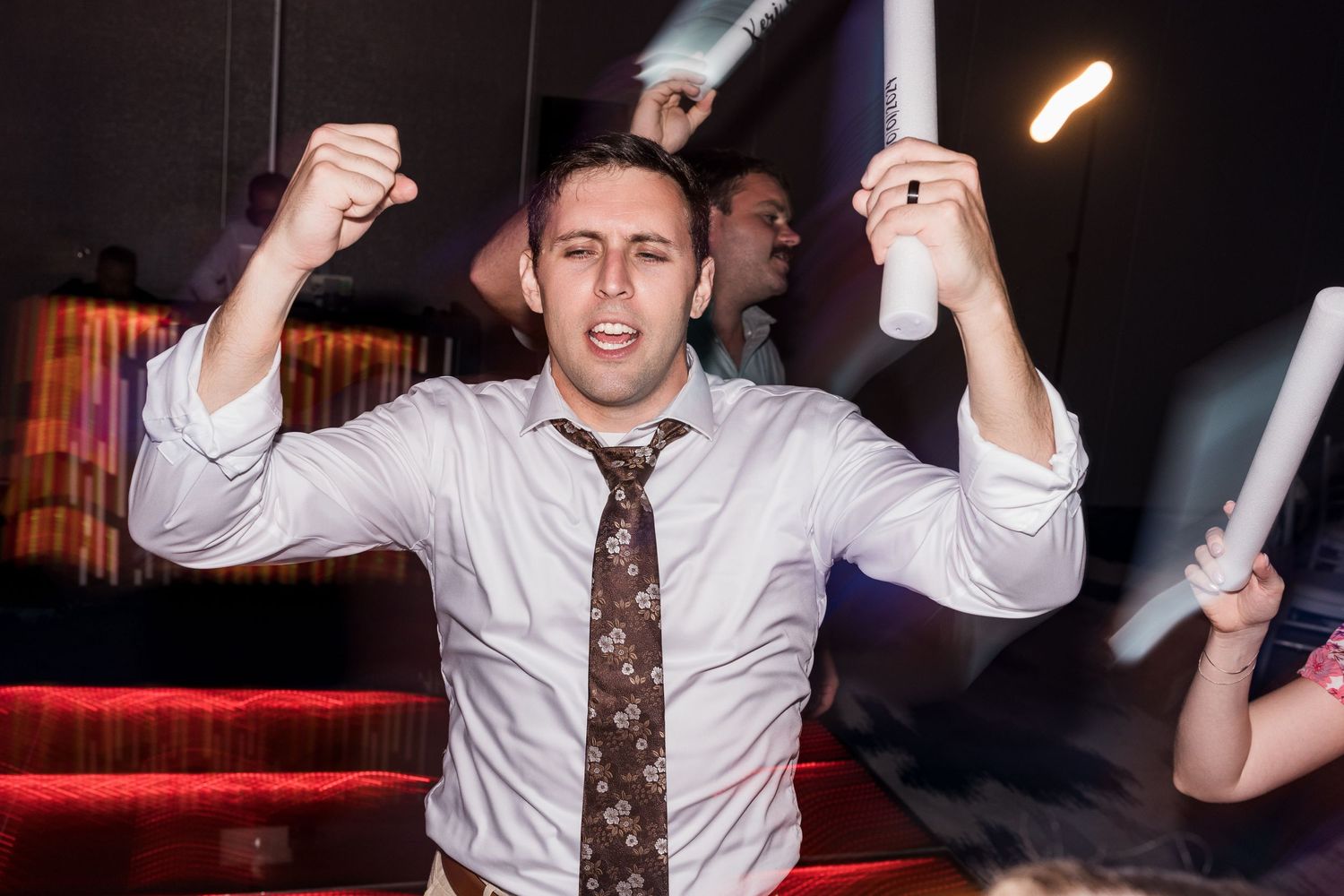 Man in white shirt and tie celebrating energetically on the dance floor.