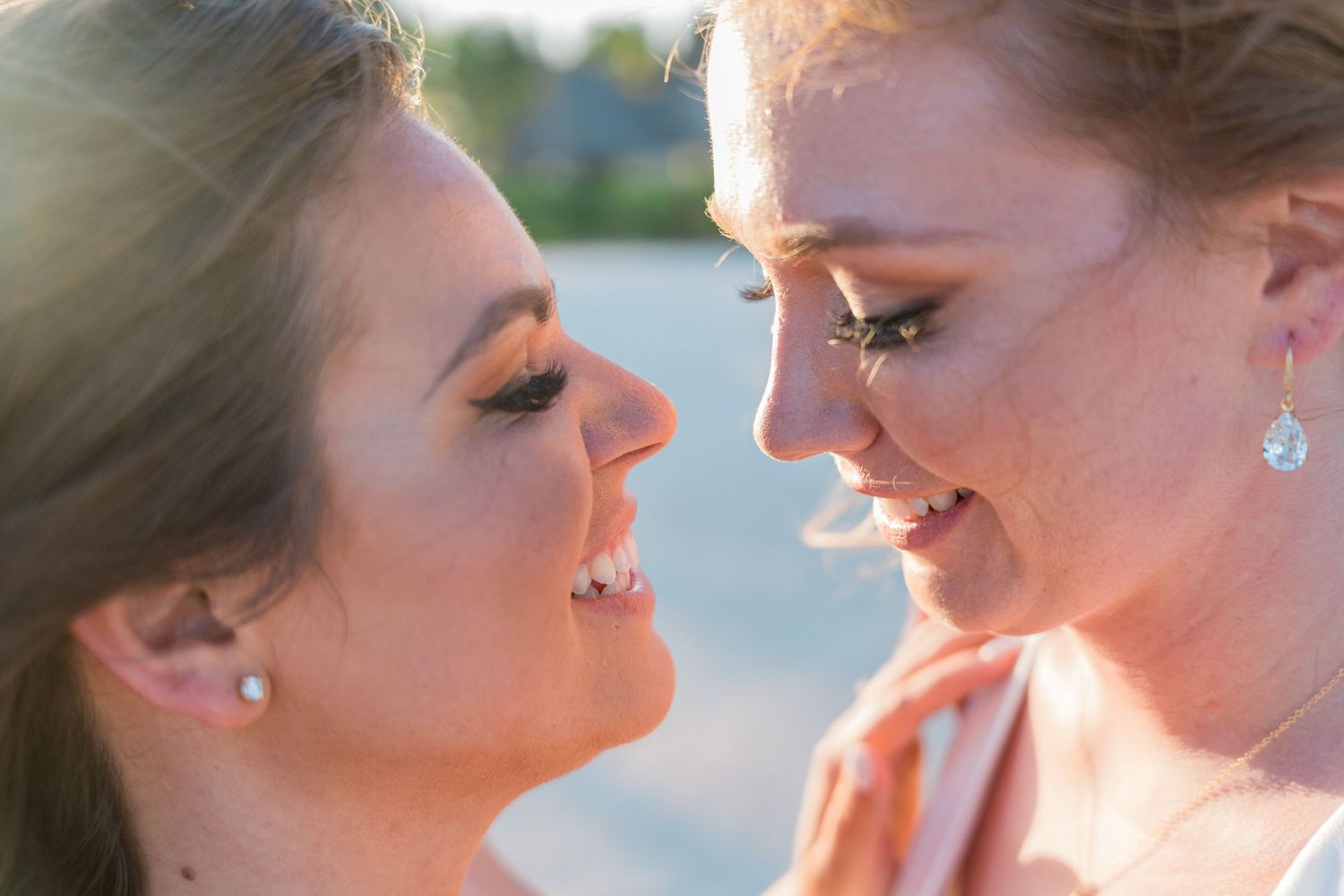 Close-up of two brides gazing at each other lovingly in golden sunset light.