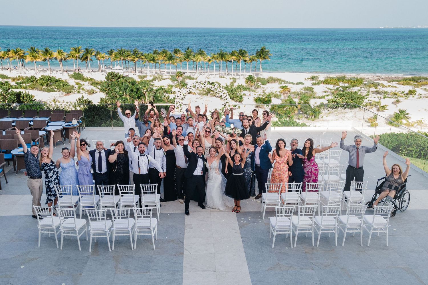 Wedding party and guests celebrate together at stunning oceanfront venue after beach ceremony.
