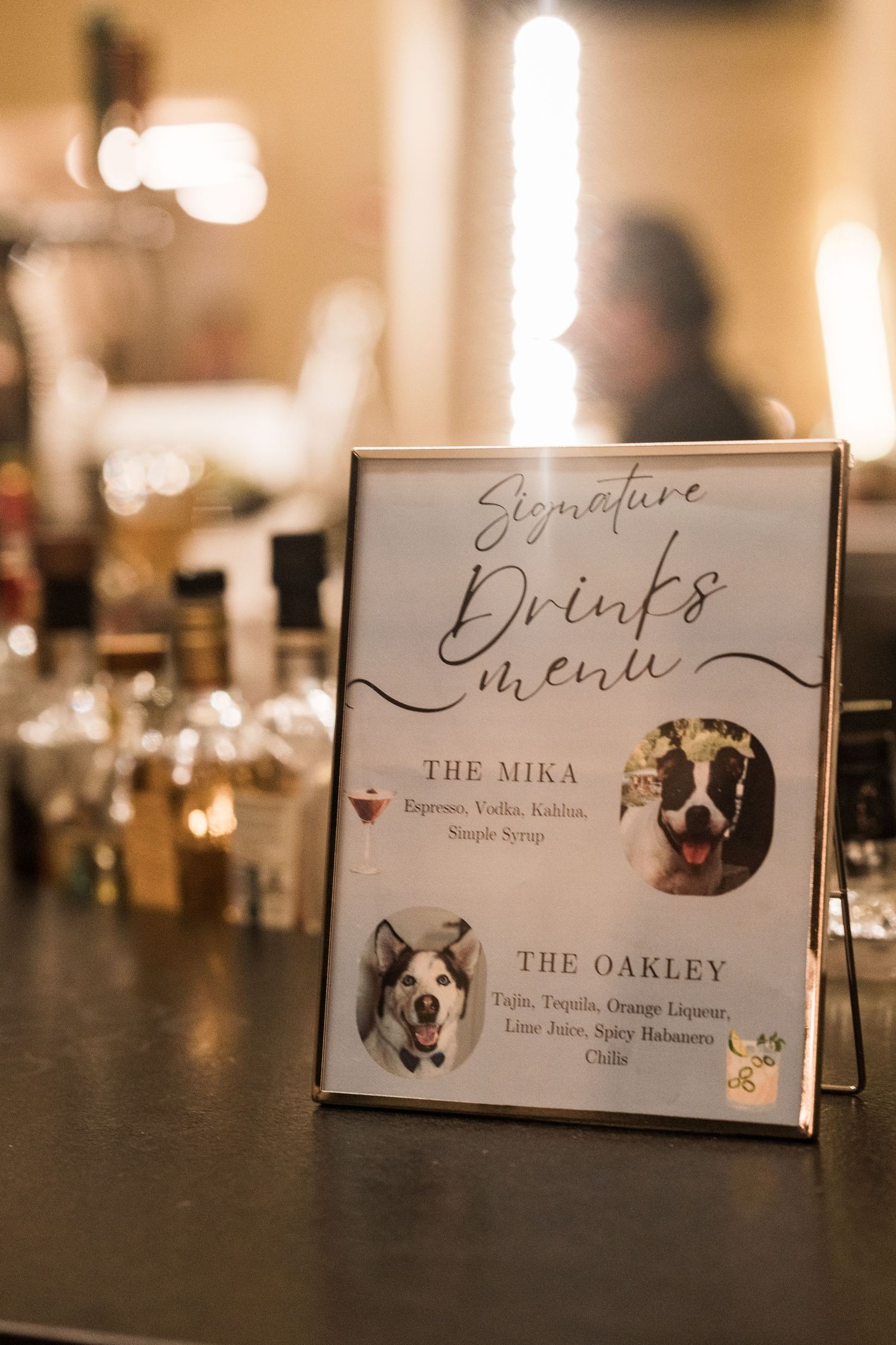 Signature drinks menu display featuring two cocktails named after dogs, The Mika and The Oakley, at a wedding bar.