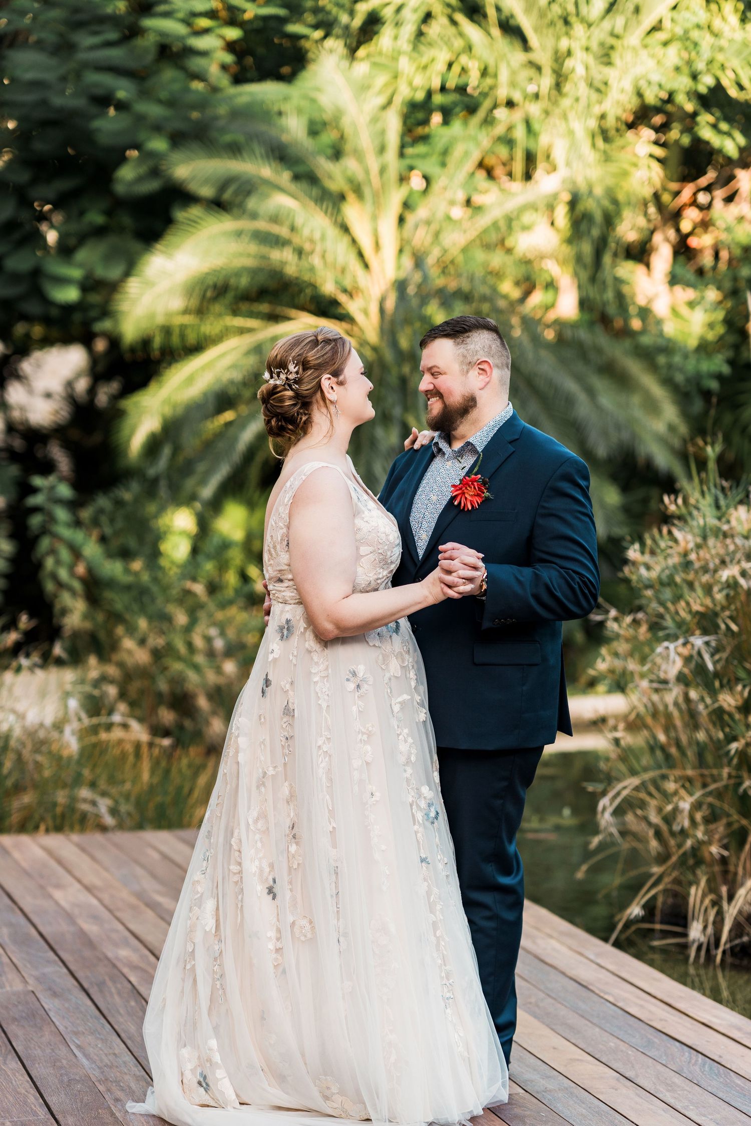 Secrets Akumal Wedding - Bride and groom share first dance on wooden deck surrounded by lush tropical greenery at outdoor wedding.