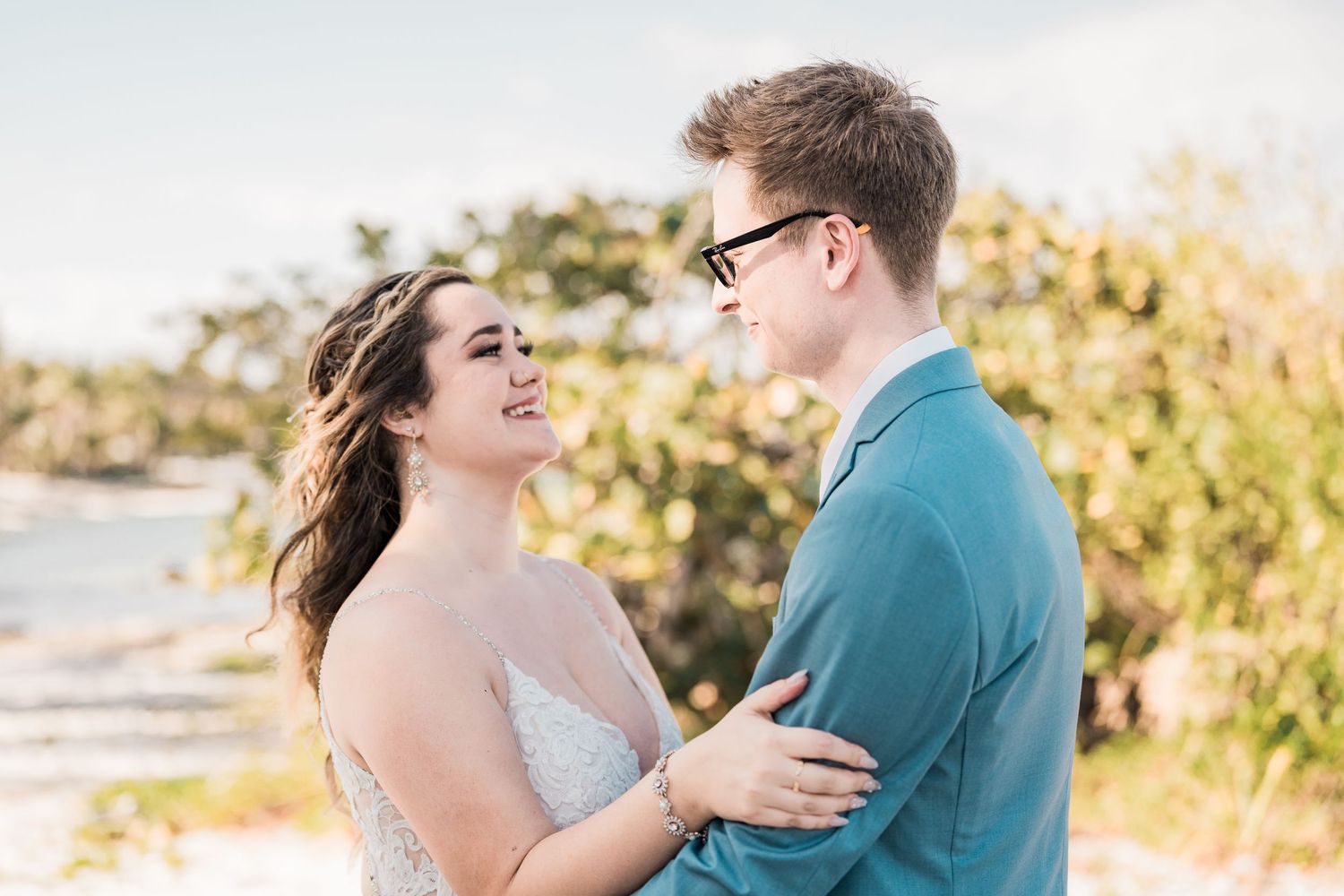 Bride and groom share a joyful moment together on a sun-kissed tropical beach.