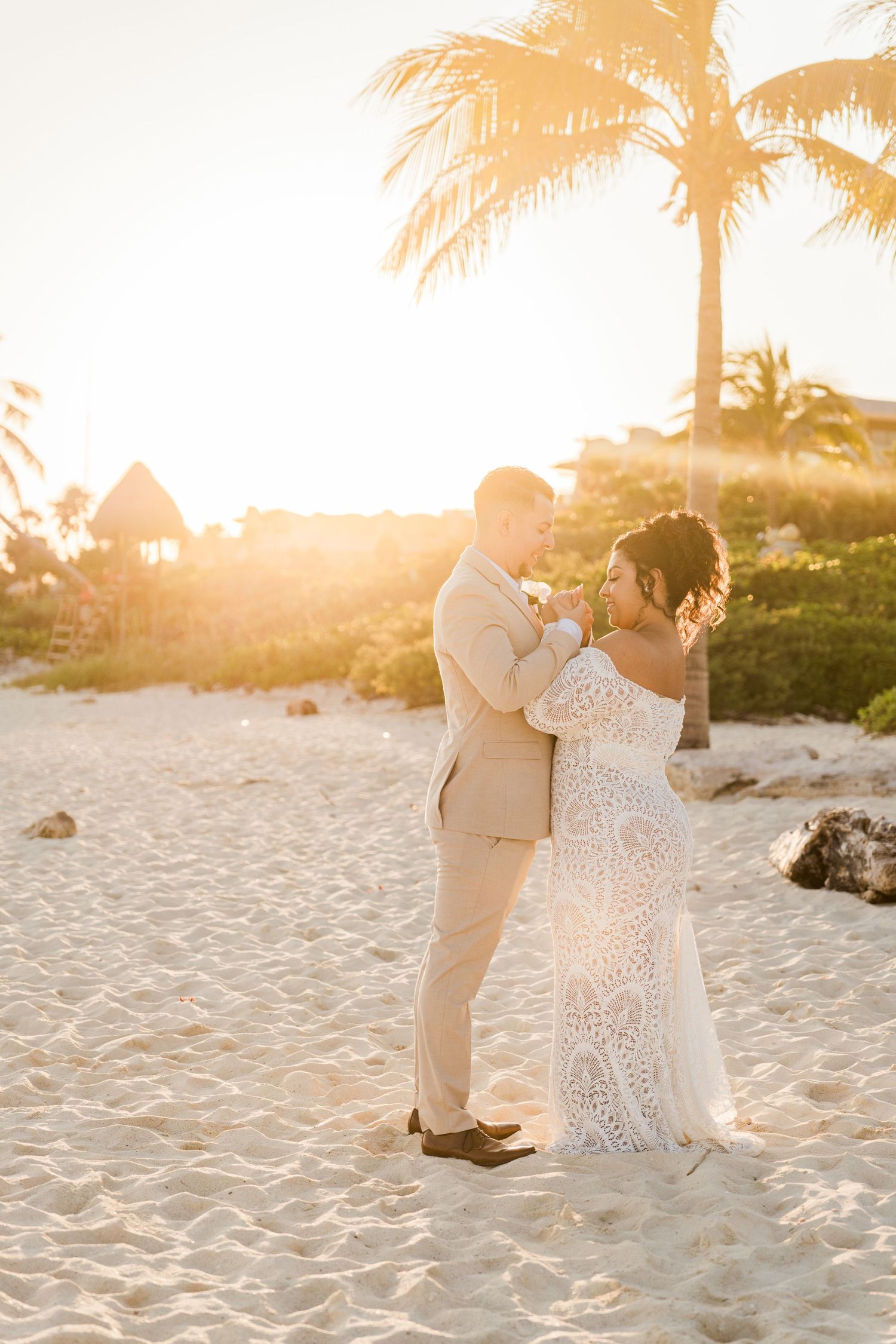 Xcaret Arte Wedding - Bride and groom share a romantic dance on a sandy beach at golden sunset