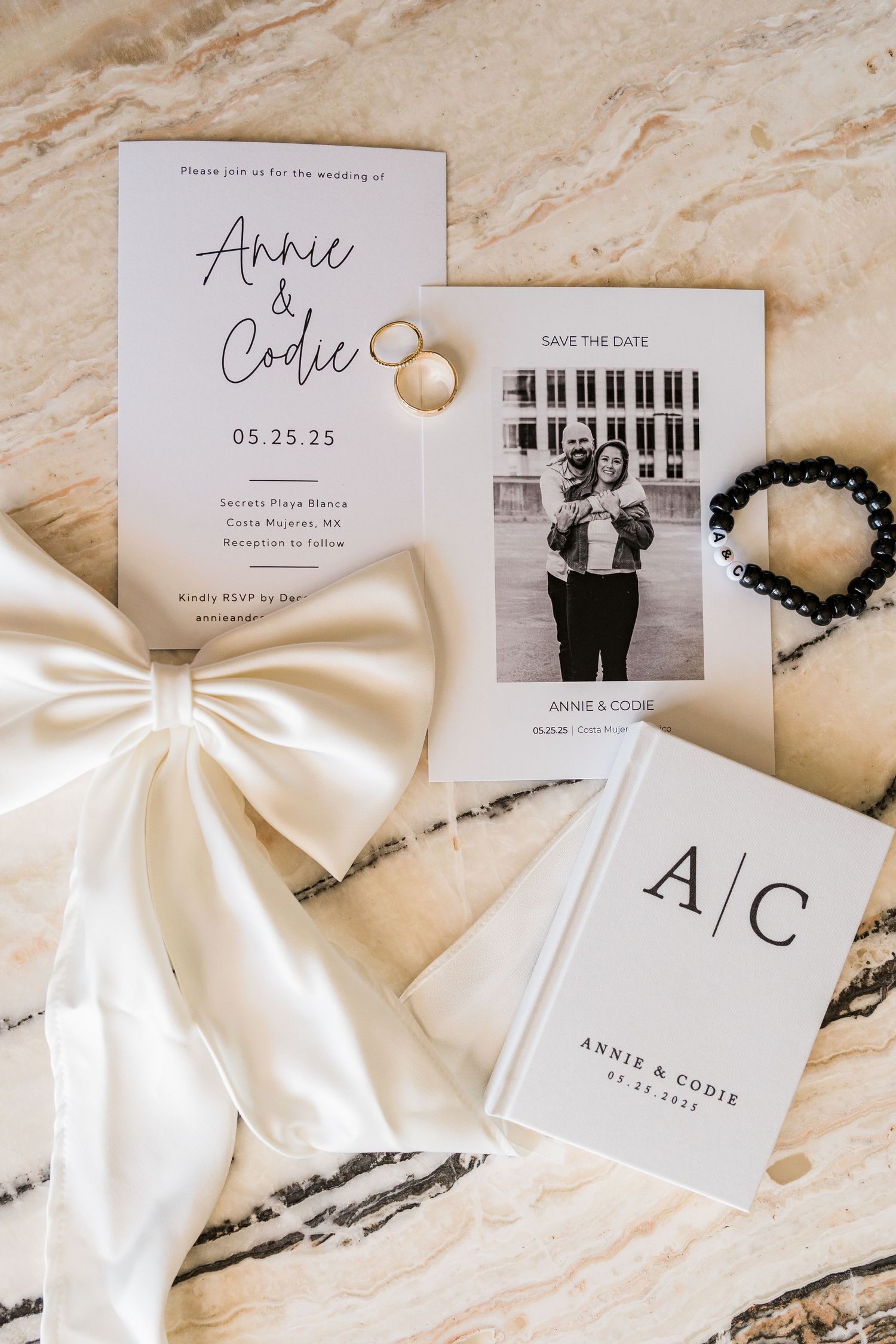 Elegant wedding stationery suite featuring Annie and Codie invitation, save the date, monogram booklet, rings, and satin bow.