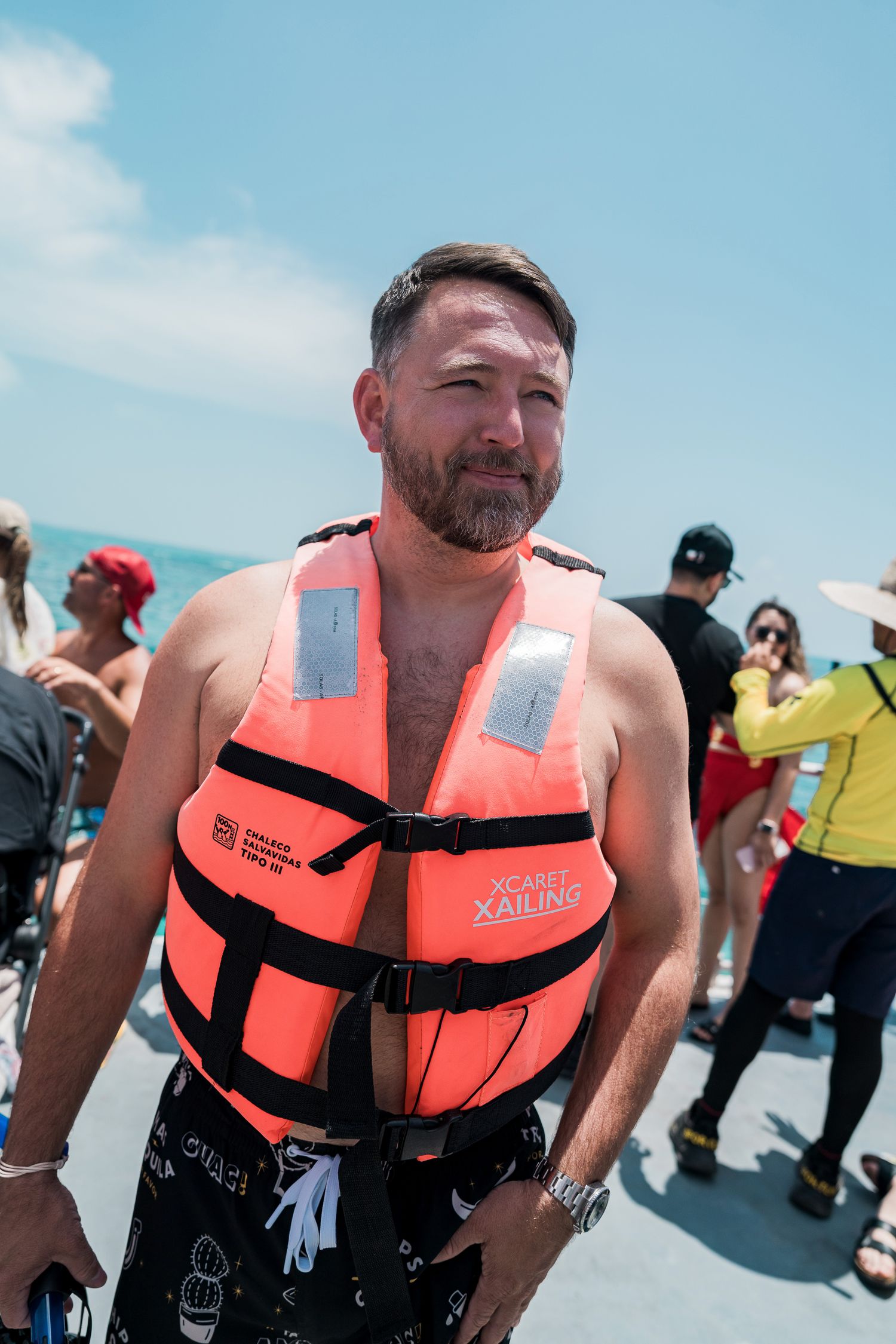 Riviera Maya Multi Day wedding - Man wearing orange life vest on a boat deck during a sunny day water activity excursion.