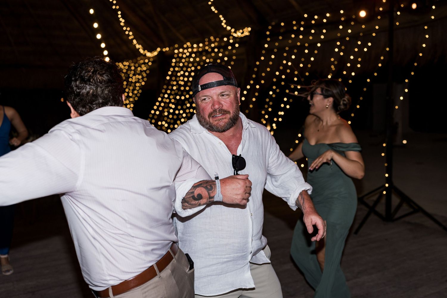 Energetic wedding guest dances with microphone at lively outdoor tropical wedding reception.