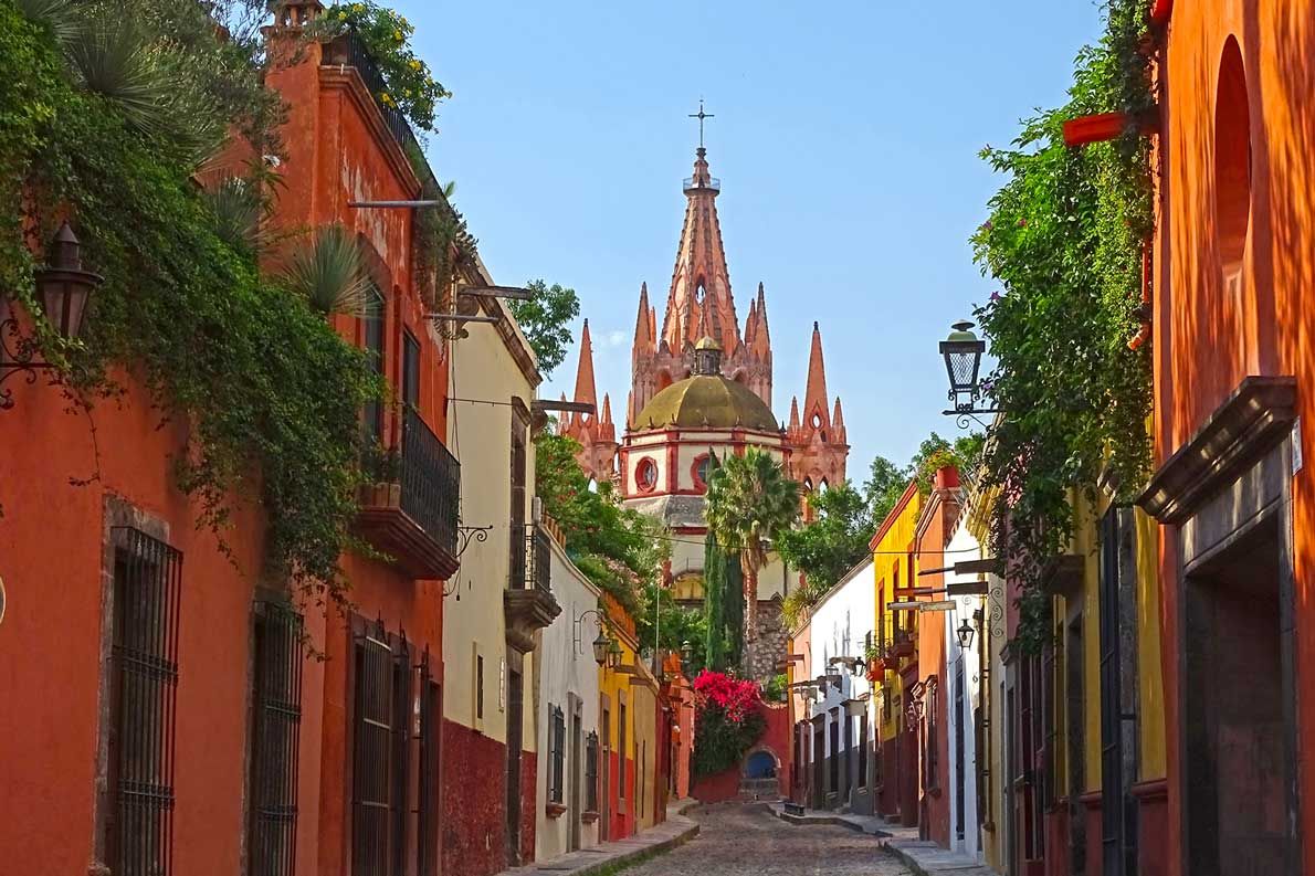 Colorful cobblestone street in San Miguel de Allende with the Parroquia cathedral in background.