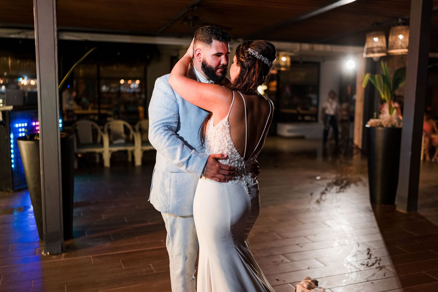 Bride and groom sharing intimate first dance embrace under warm lighting on the wedding reception dance floor.