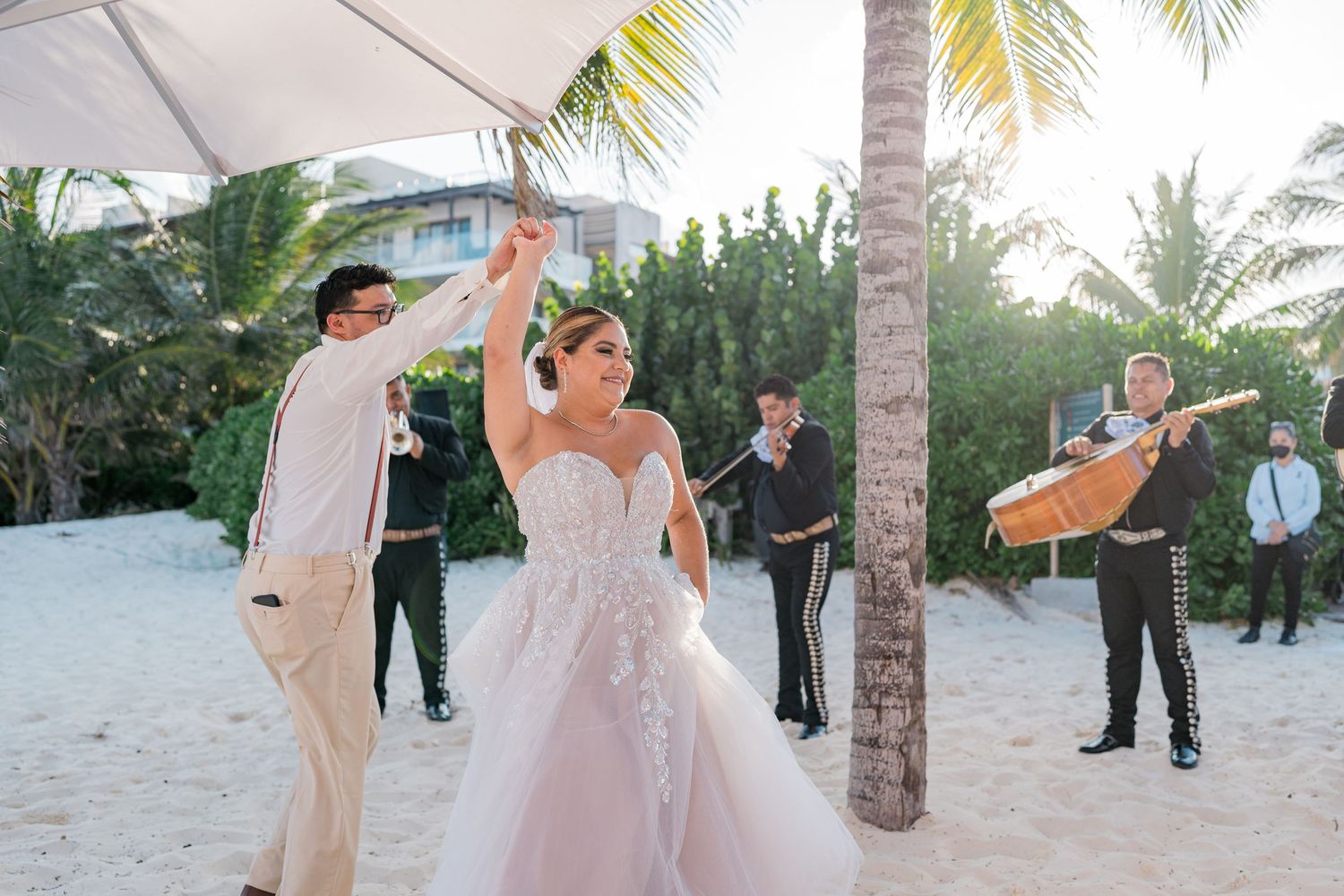Bride and groom dance together on the beach as a mariachi band performs at their outdoor wedding reception.