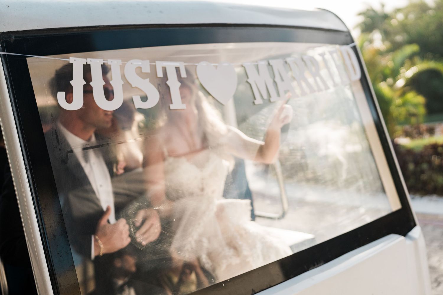 A just married couple seen through a car rear window with Just Married text, celebrating their wedding day.