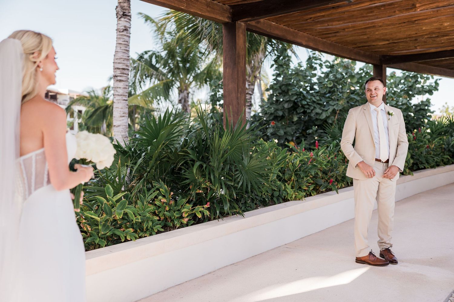 Bride and groom share emotional first look moment at outdoor tropical resort wedding venue.