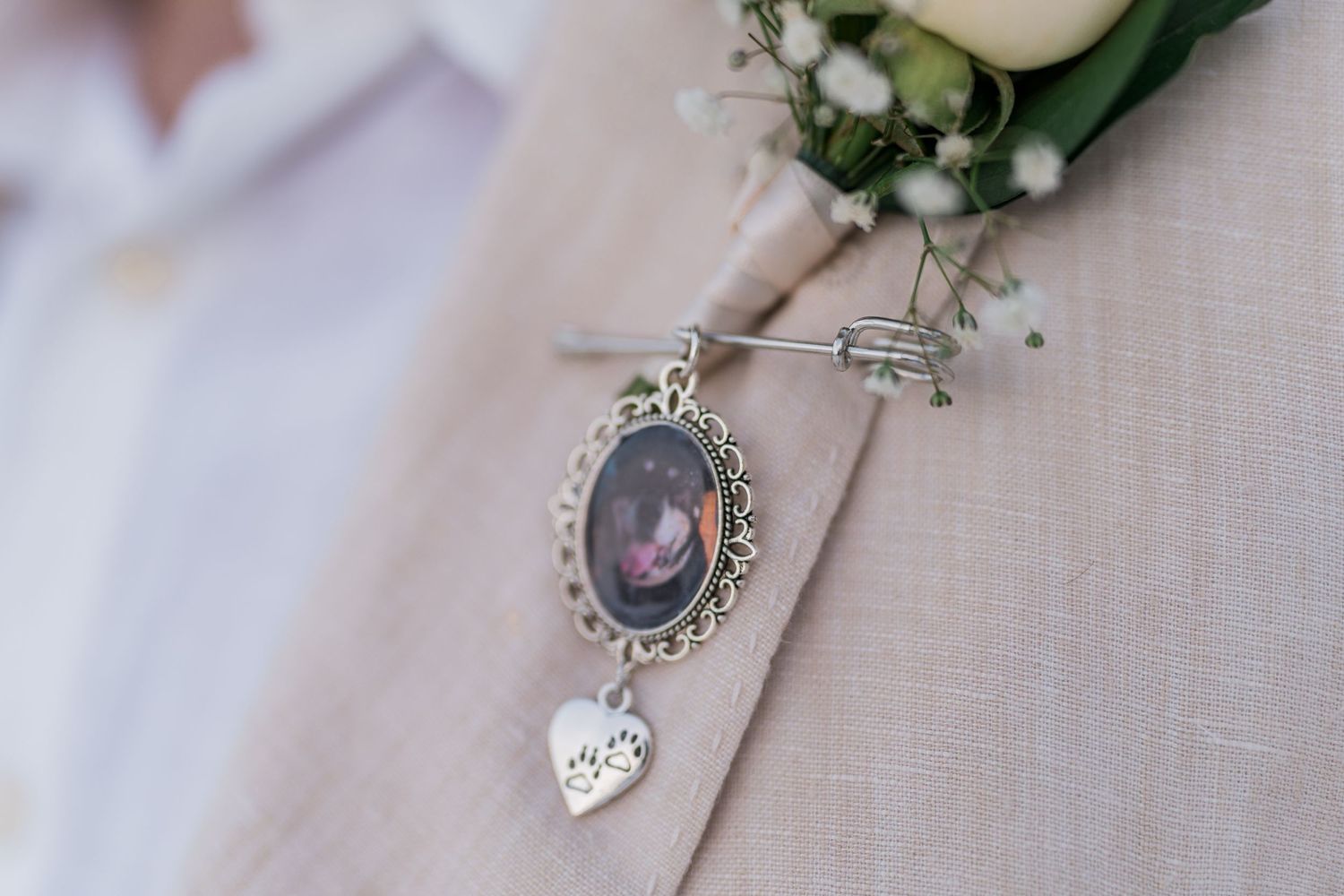 Close-up of memorial photo charm pinned to groom's tan wedding suit lapel.