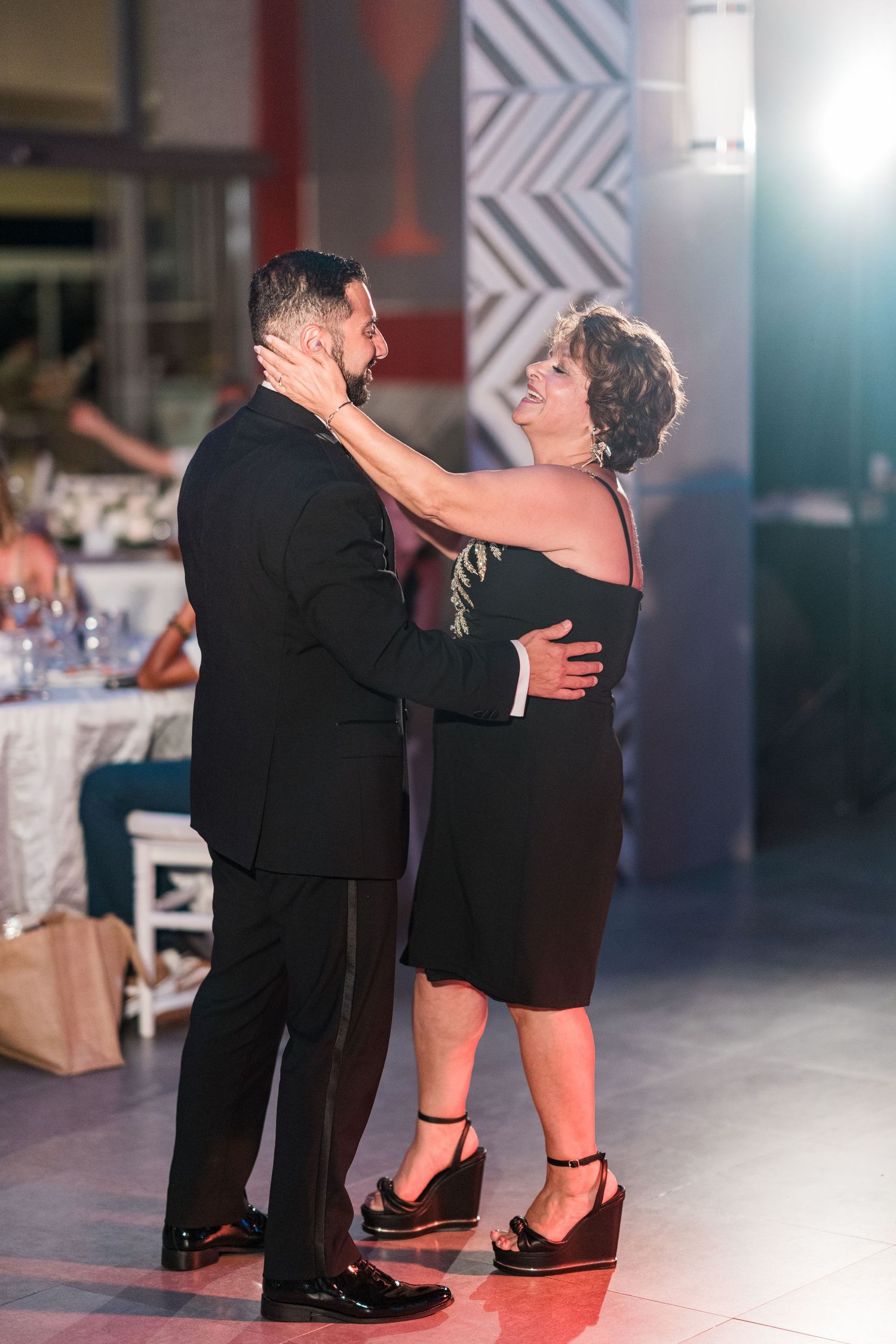 Mother and son share emotional dance at wedding reception, embracing on the dance floor.