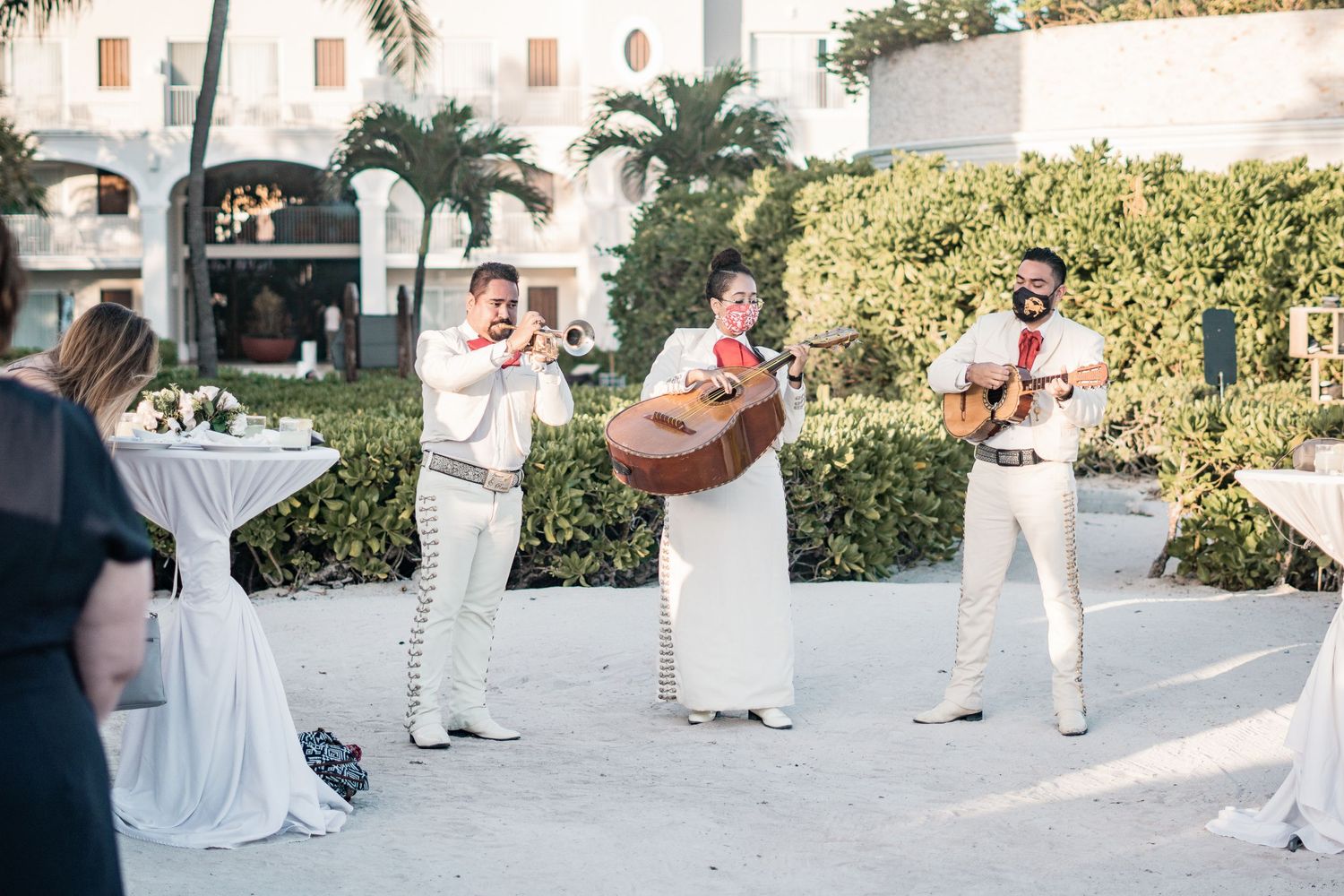 Mariachi band in white suits performs for guests at elegant tropical beach wedding reception.