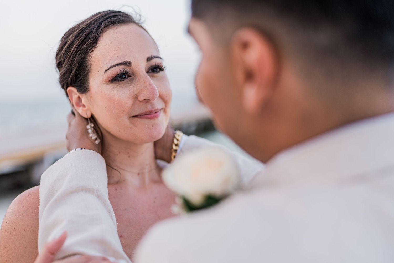 Bride gazing lovingly at groom during beach wedding ceremony.
