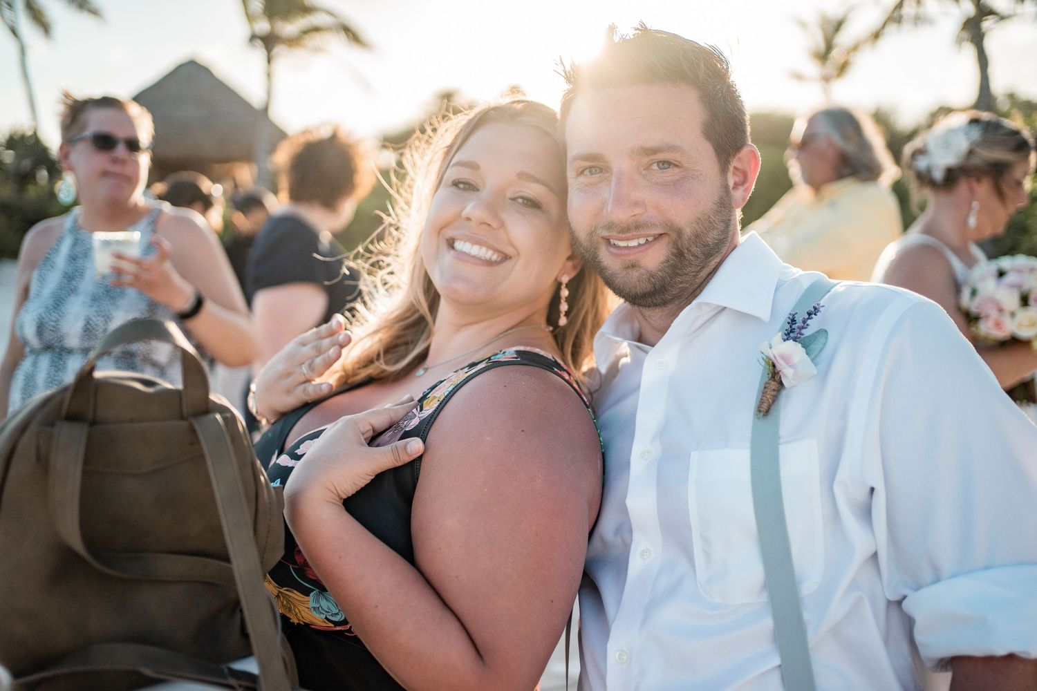 Smiling couple poses together at golden hour during tropical beach wedding reception celebration.