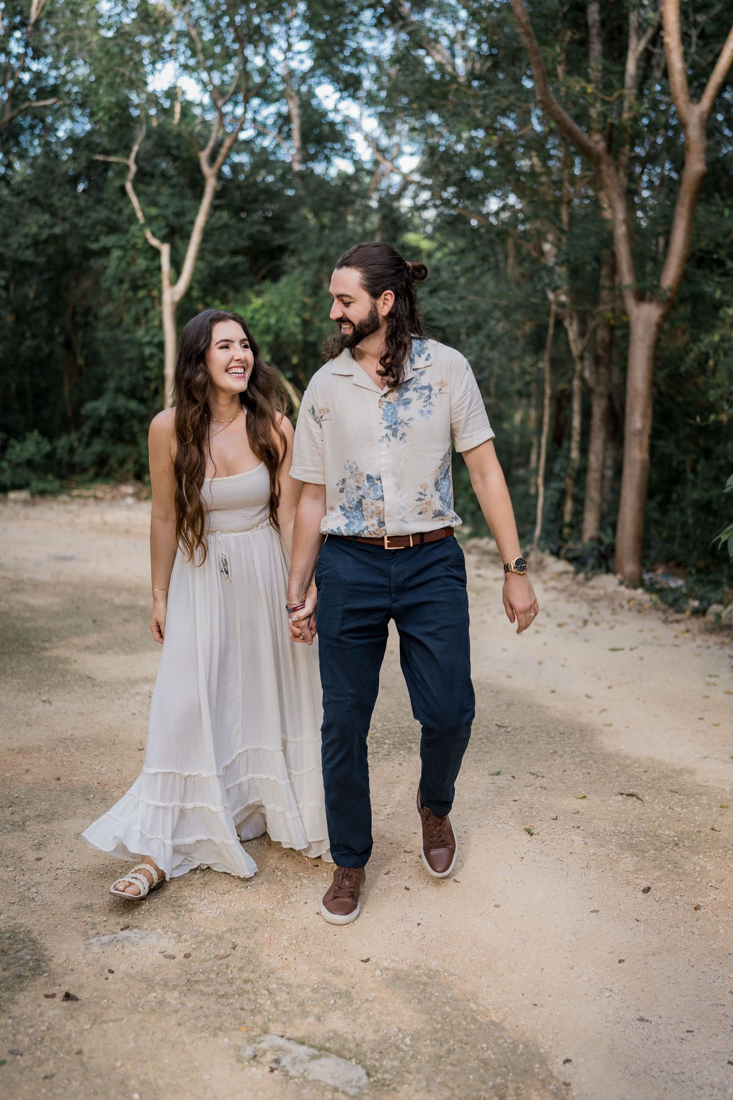 cenote couple photoshoot, couple walking in the jungle while they look each other and laugh - Luis Tovilla Wedding Photographer