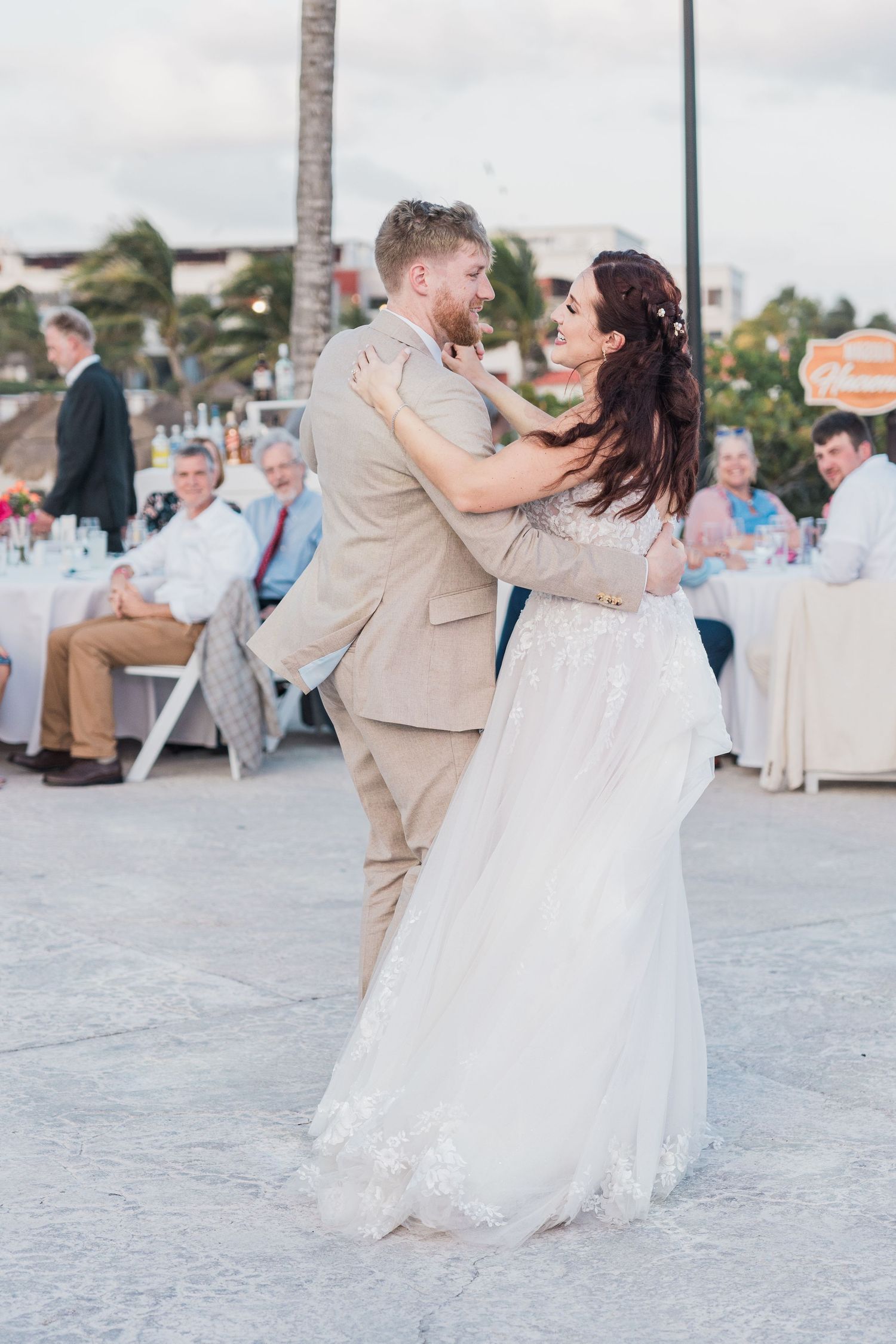 Newlyweds share a romantic first dance at their outdoor destination wedding reception at dusk.