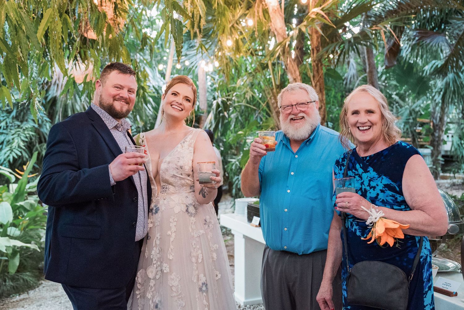 Secrets Akumal Wedding - Four guests in formal attire toasting with champagne glasses at an elegant outdoor wedding reception.