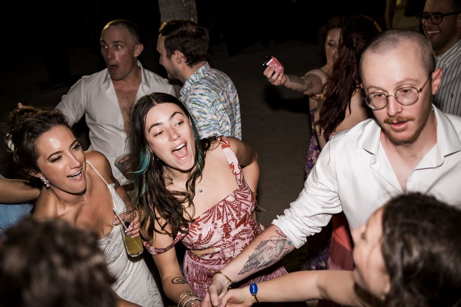 Group of young adults dancing and laughing at an outdoor night party celebration.
