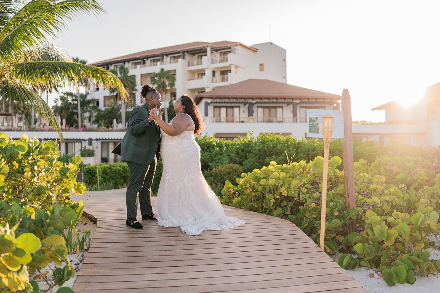 Newlyweds share a romantic dance on a boardwalk at golden hour beach resort.
