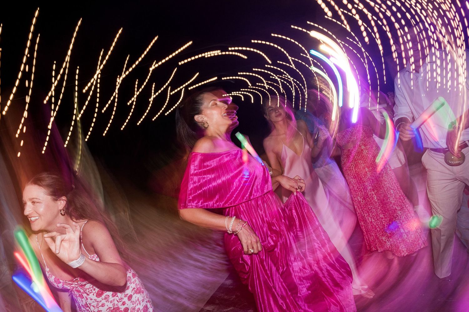 Hotel Xcaret México People dancing at a vibrant party with colorful swirling lights and motion blur effects.